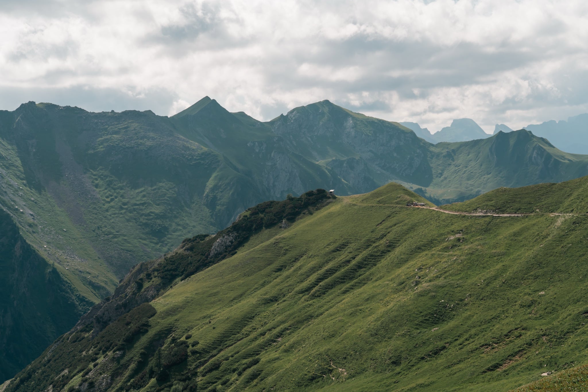 A green alpine ridge under a soft cloud-covered sky