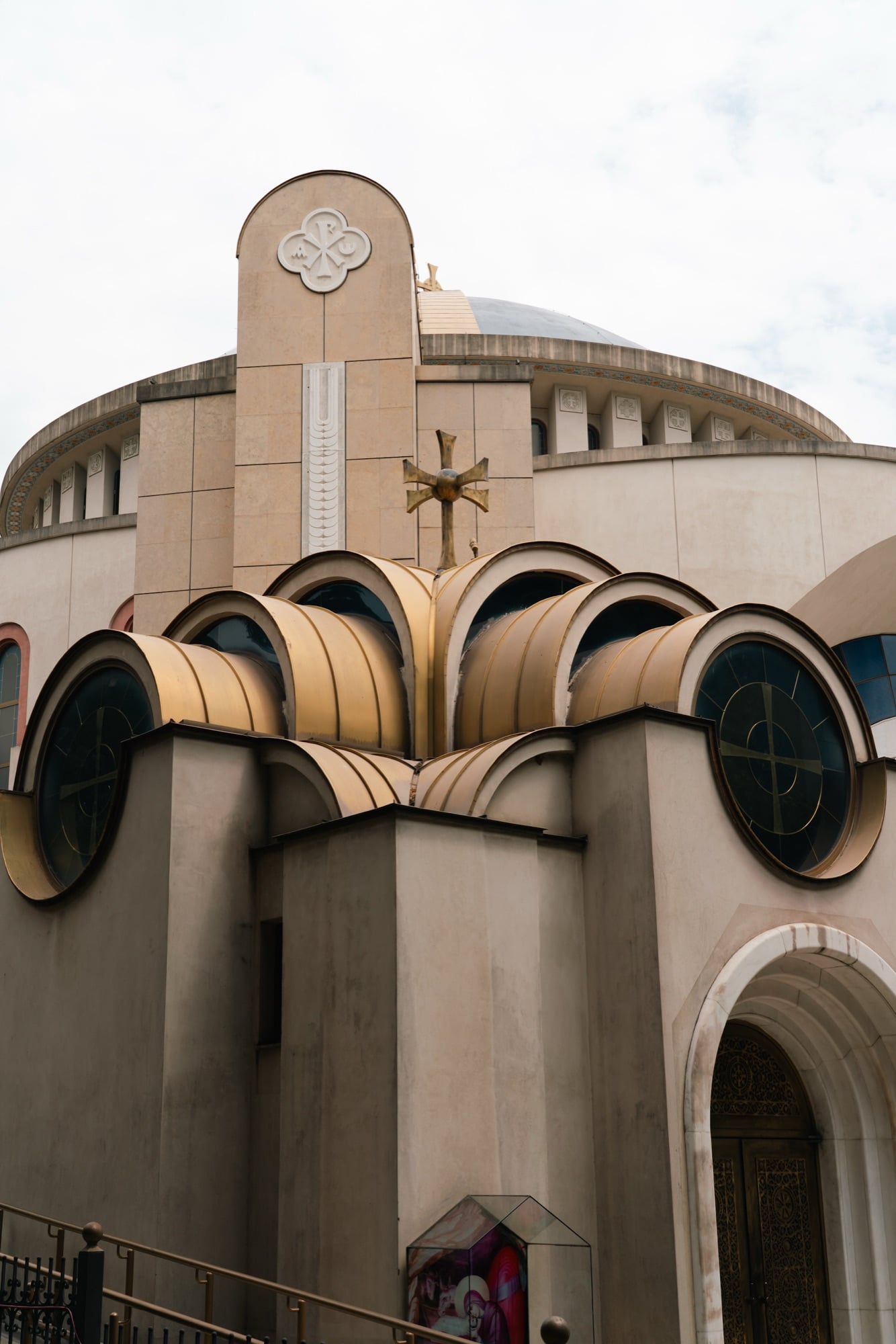 The dome and gold-ringed round windows of the Resurrection of Christ Orthodox Cathedral of Tirana beneath a cross