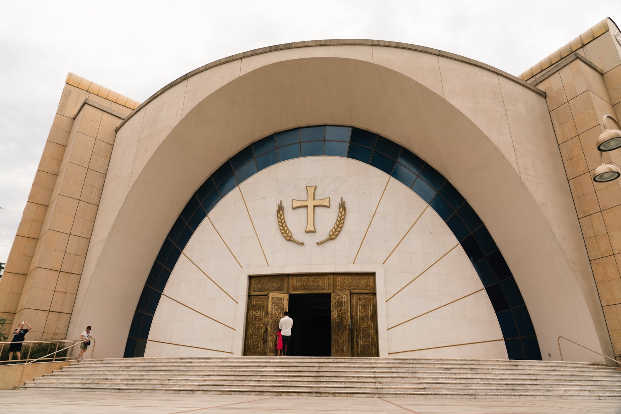 The sweeping arched entrance of the Resurrection of Christ Orthodox Cathedral, a gilded cross above the bronze doors