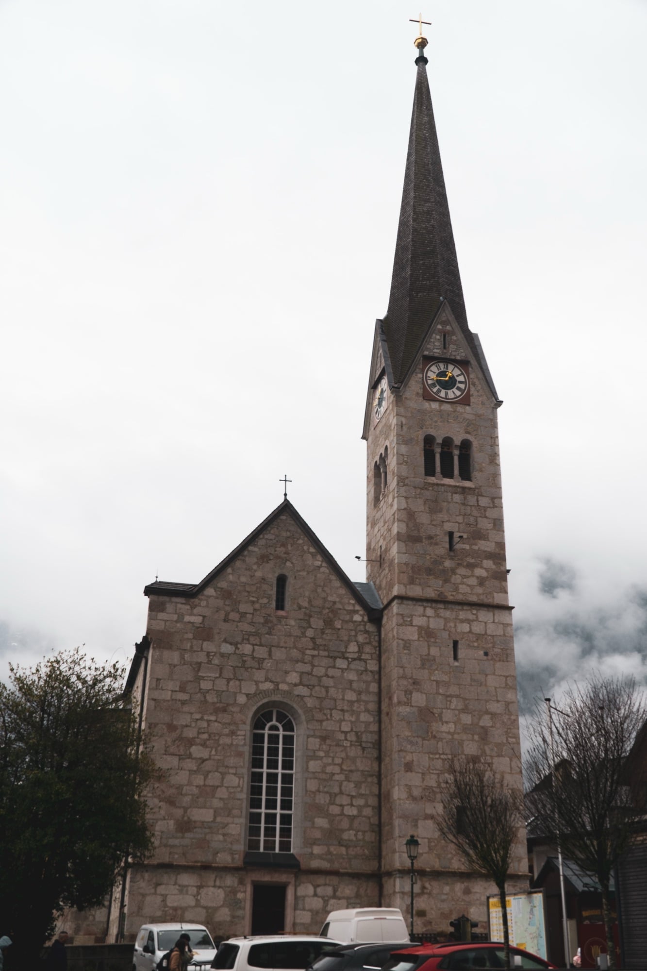 The slender spire of the Evangelical church rising into the mist, Hallstatt