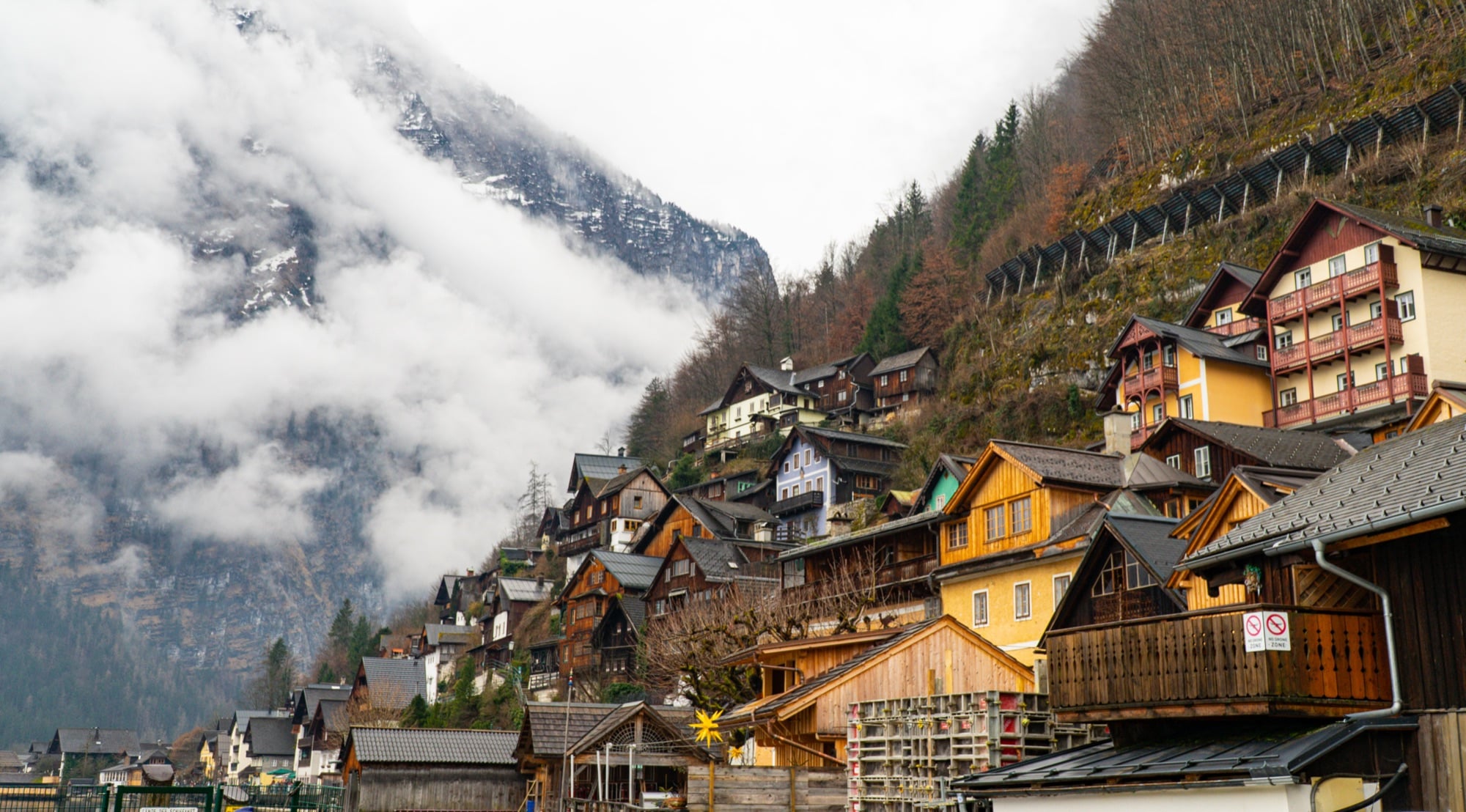 Houses stacked up the steep mountainside under drifting mist, Hallstatt