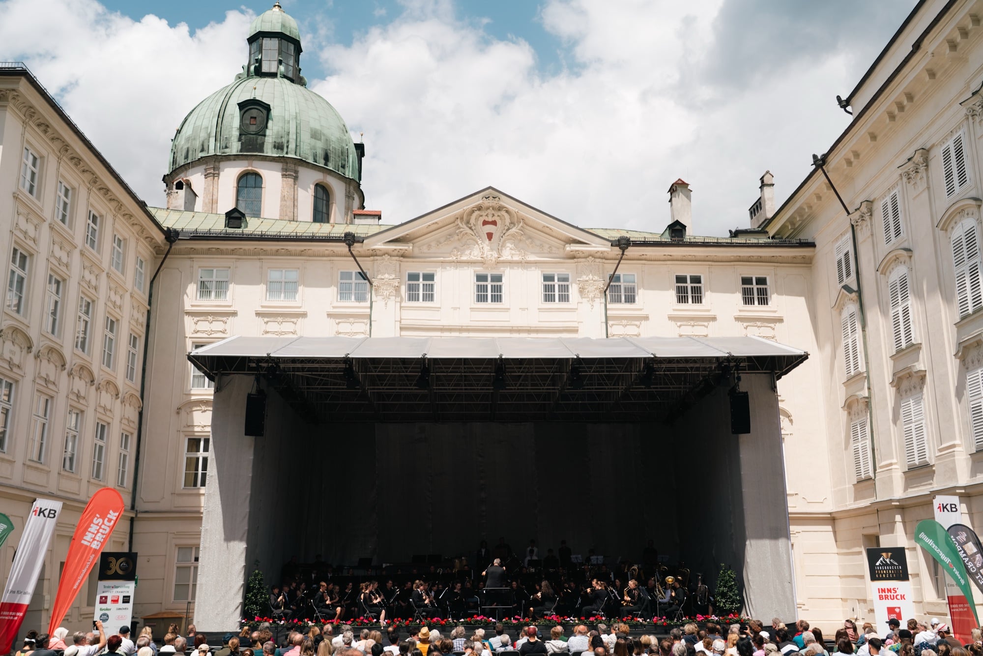 A concert stage set up before the cathedral dome, an audience gathered, Innsbruck