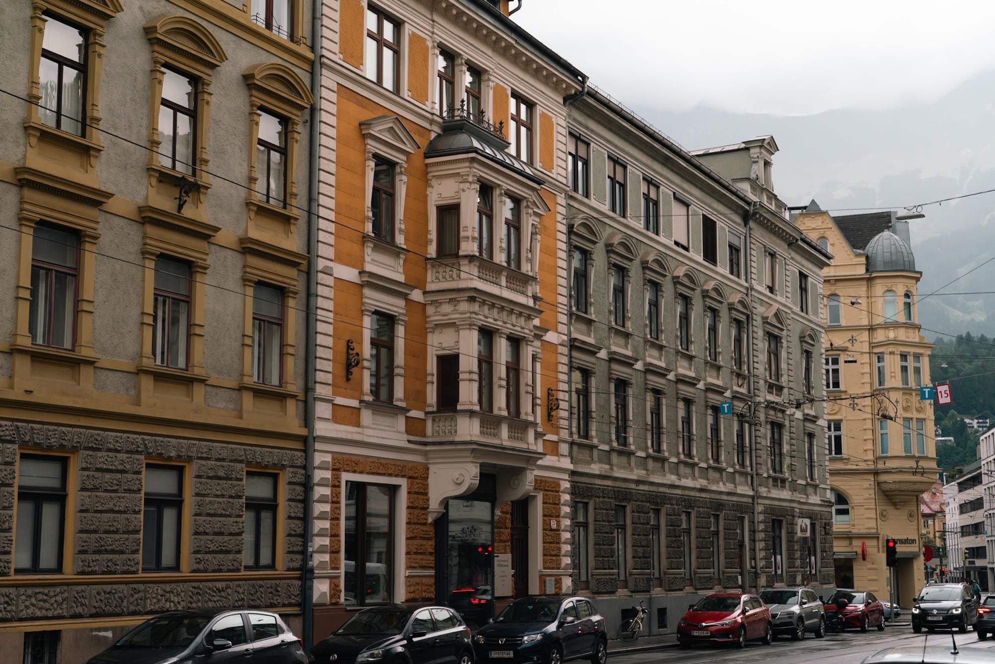 A row of ornate painted facades along a street, Innsbruck