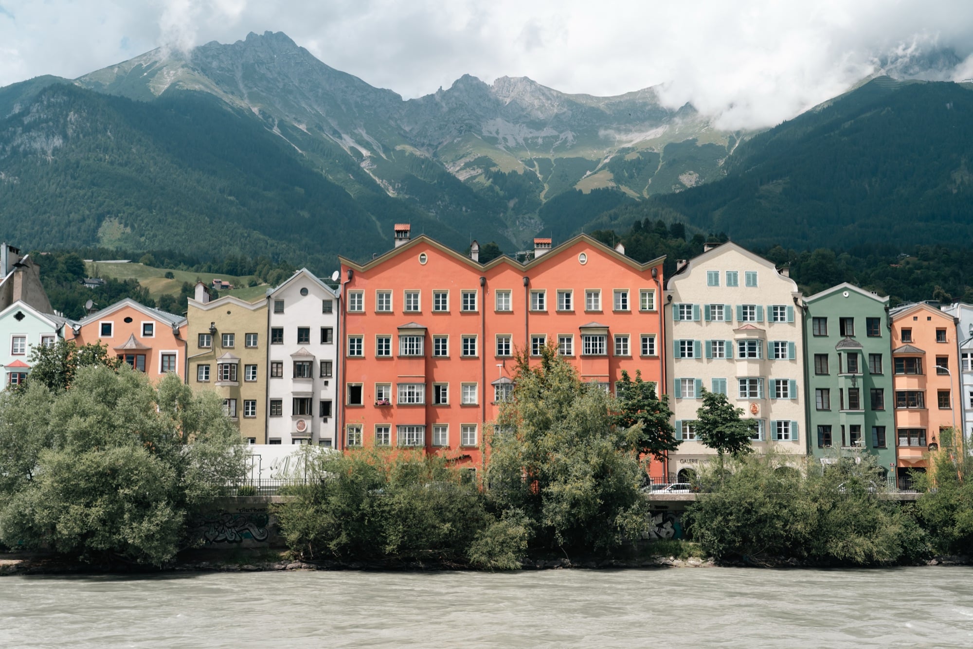 The painted Mariahilf and St. Nikolaus houses along the Inn under cloud-wrapped peaks, Innsbruck