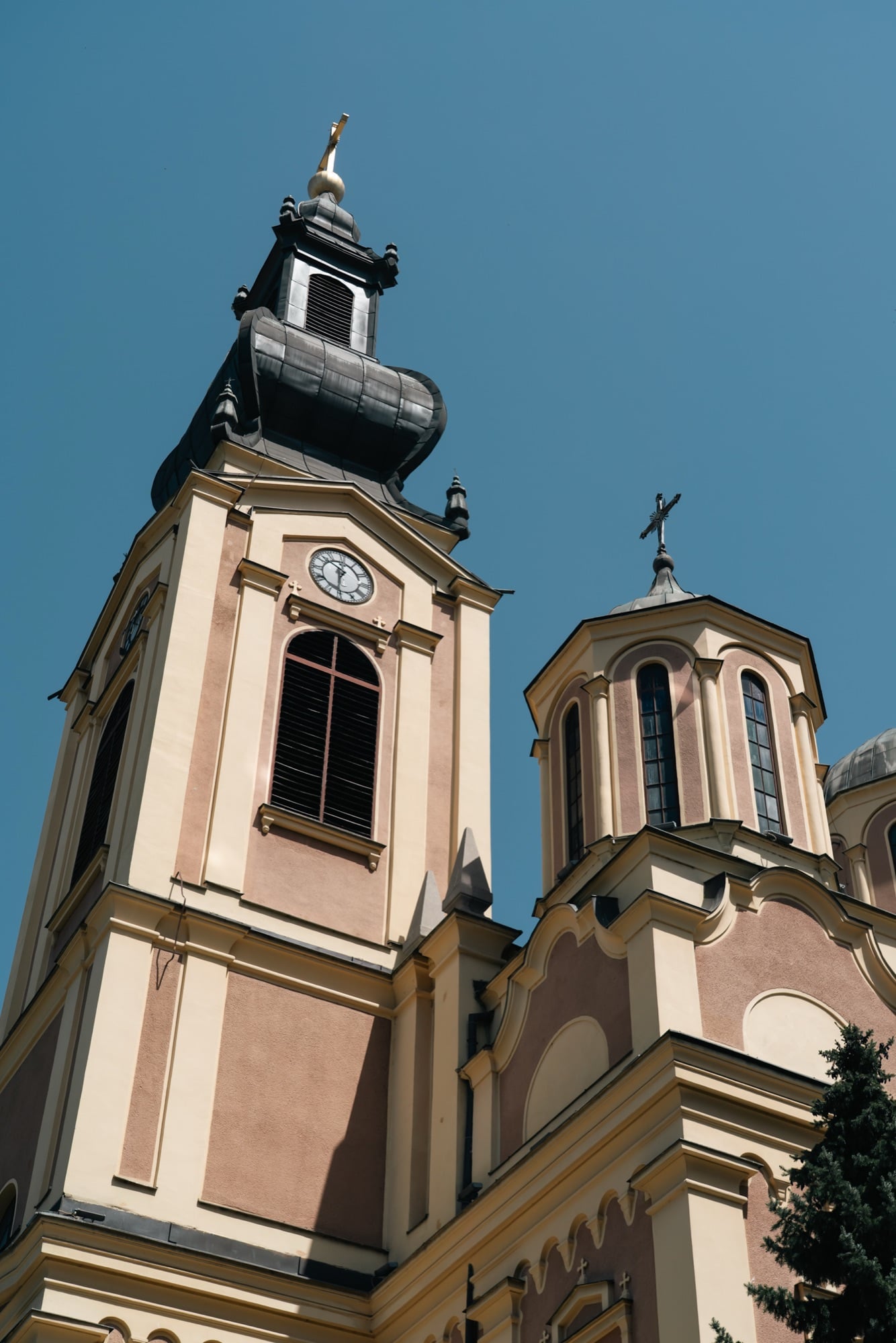 The cream-and-pink baroque bell tower and domes of Sarajevo's Serbian Orthodox Cathedral of the Nativity against a deep blue sky