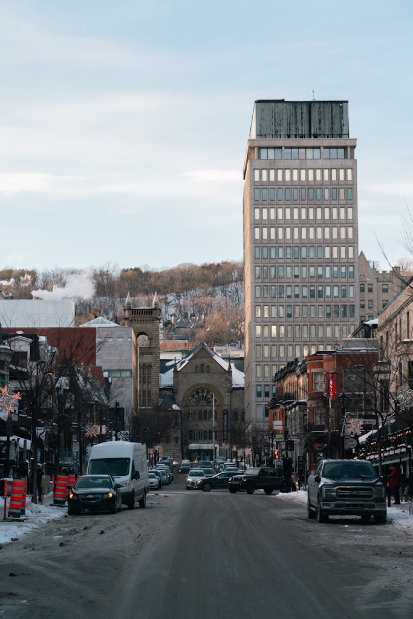 A downtown street running toward a glass tower
