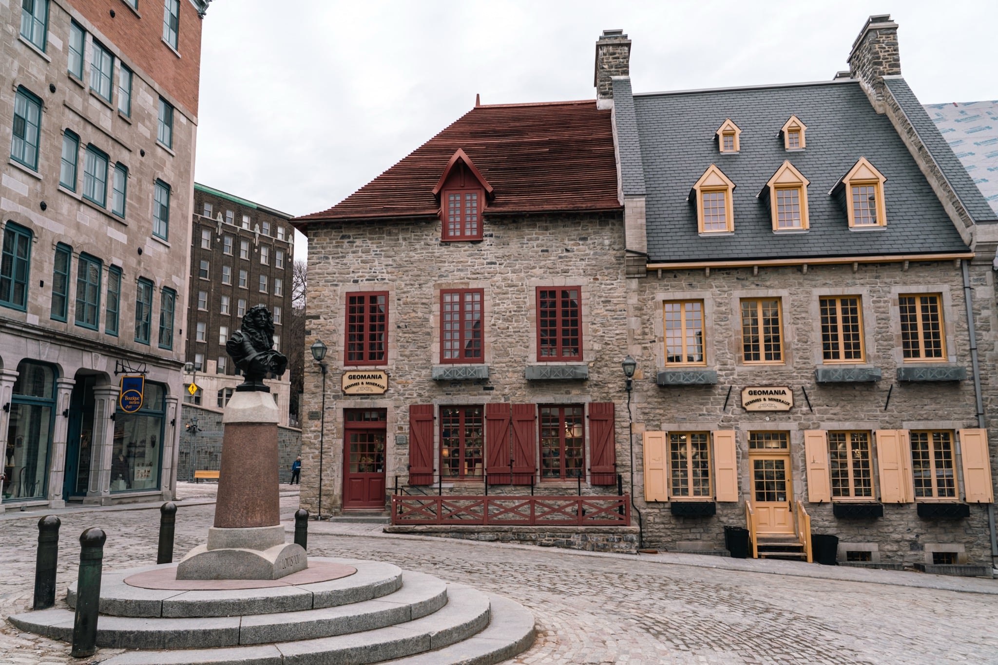 An old stone house with a red roof on a square in Old Quebec