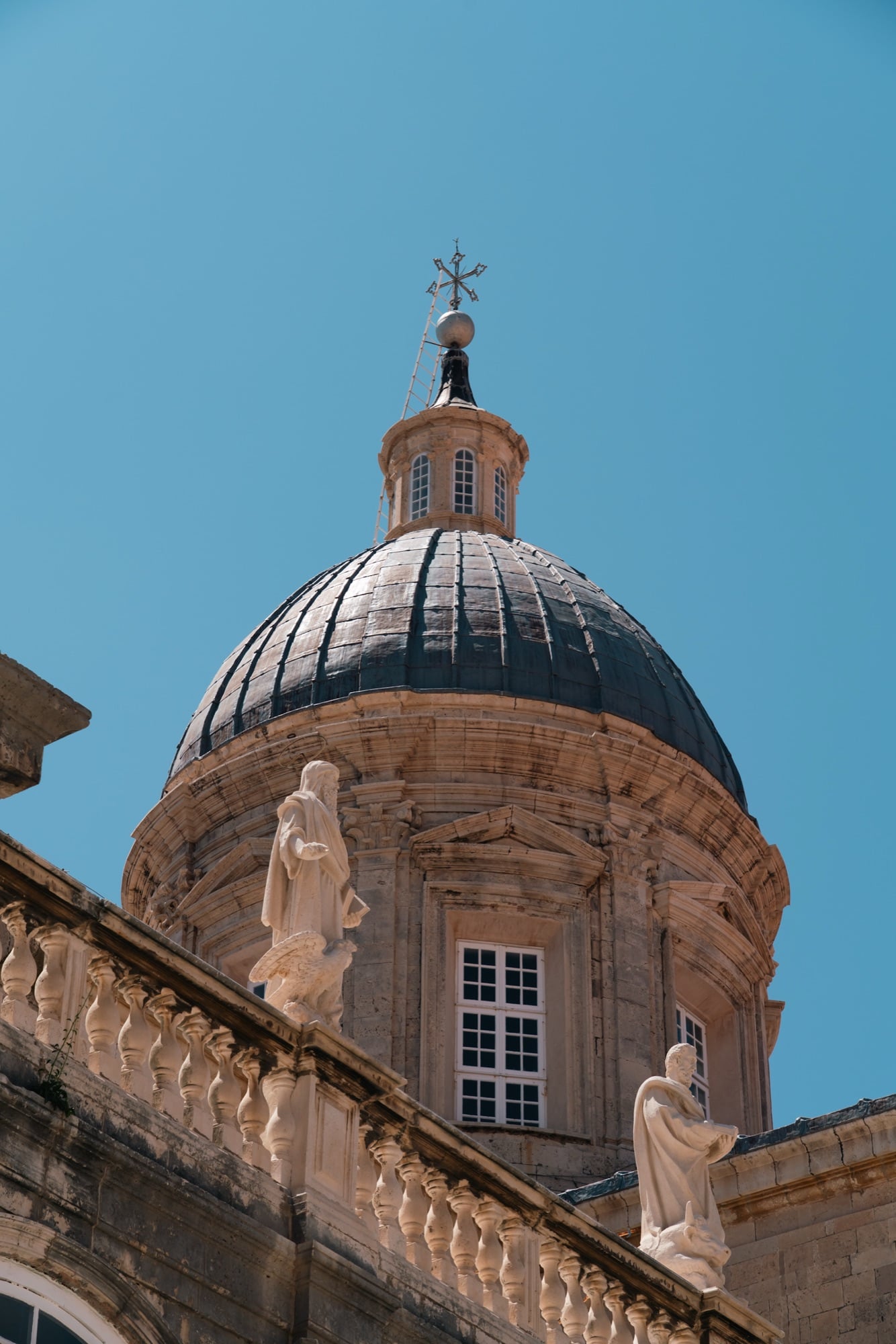 The statue-ringed dome of Dubrovnik Cathedral against a clear sky