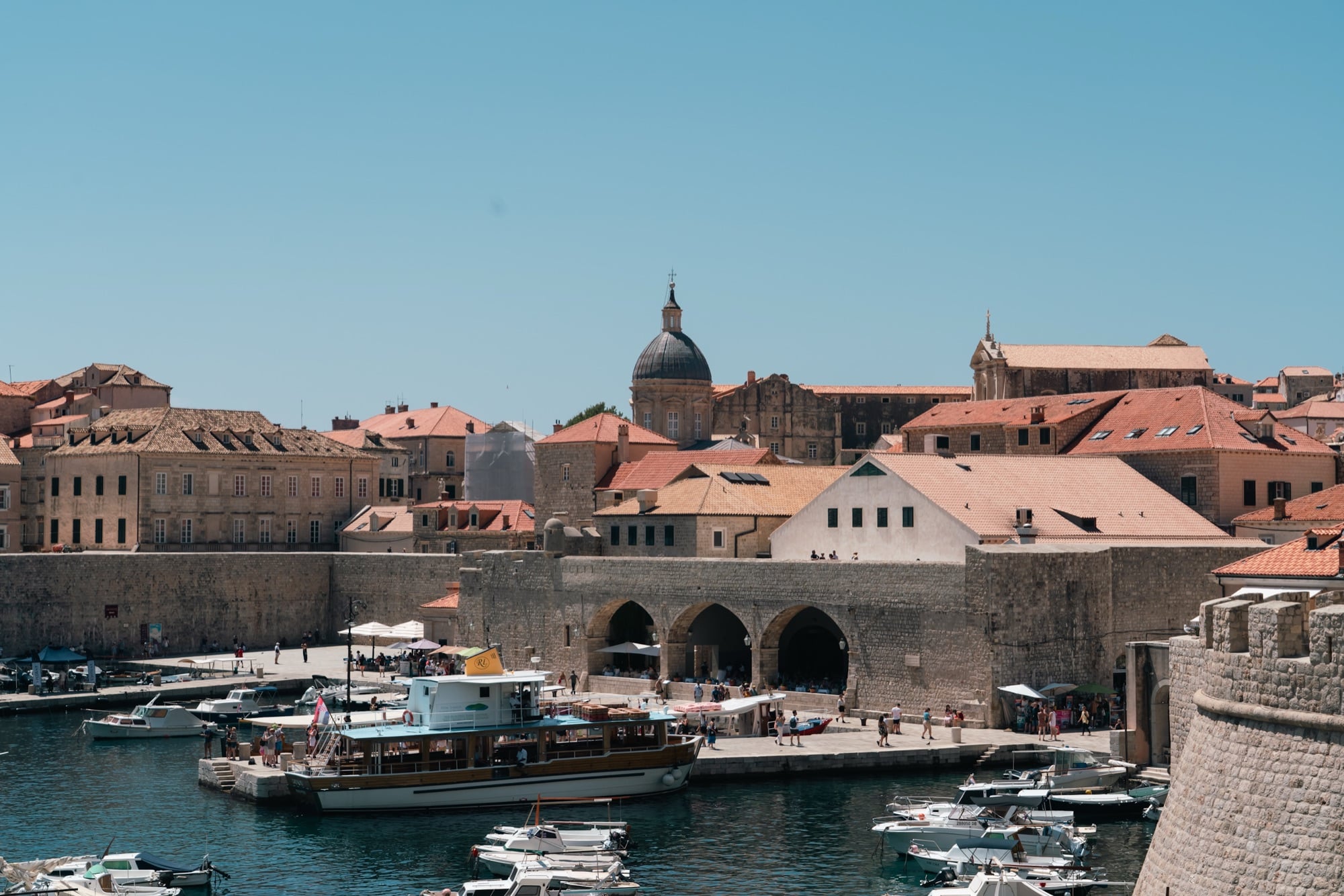 Boats moored in the Old Port beneath the city walls and bell tower, Dubrovnik