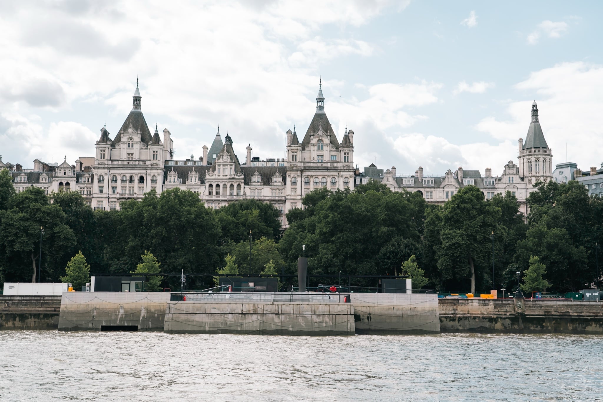 The turreted white skyline of Whitehall Court rising behind the Embankment trees