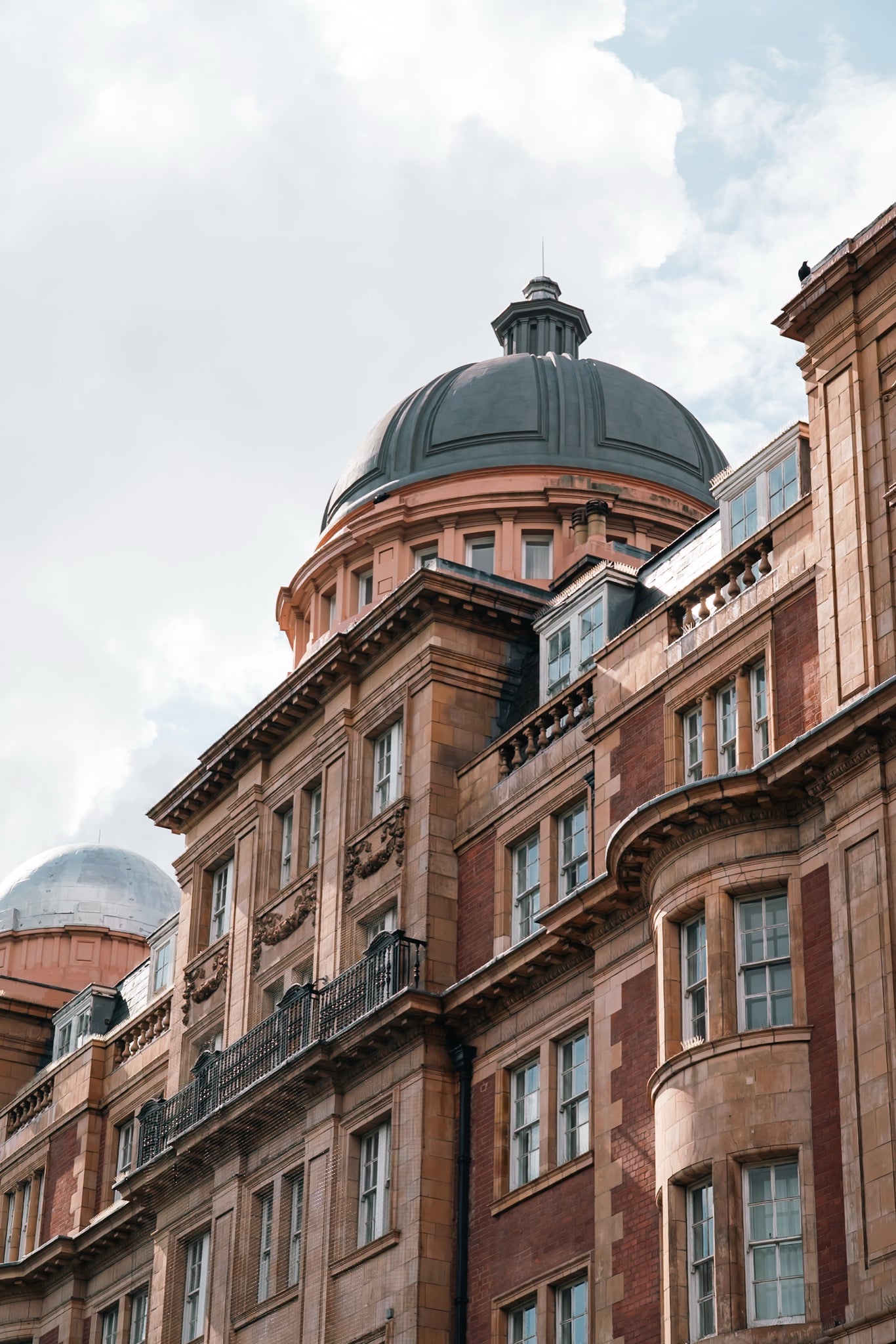 A grand corner building crowned by a dark lead dome and lantern