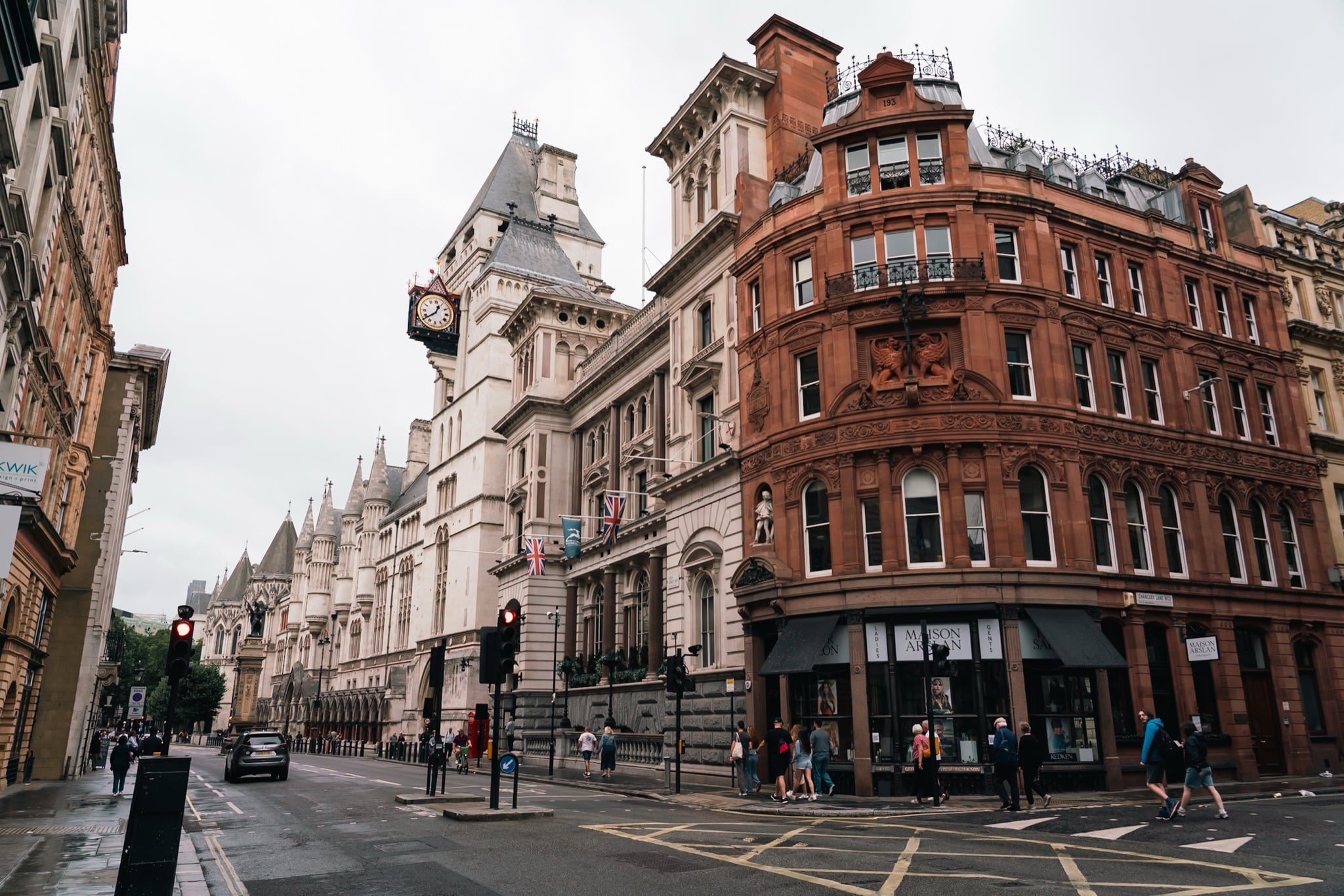 The Royal Courts of Justice and its hanging clock beside a red terracotta corner building on the Strand
