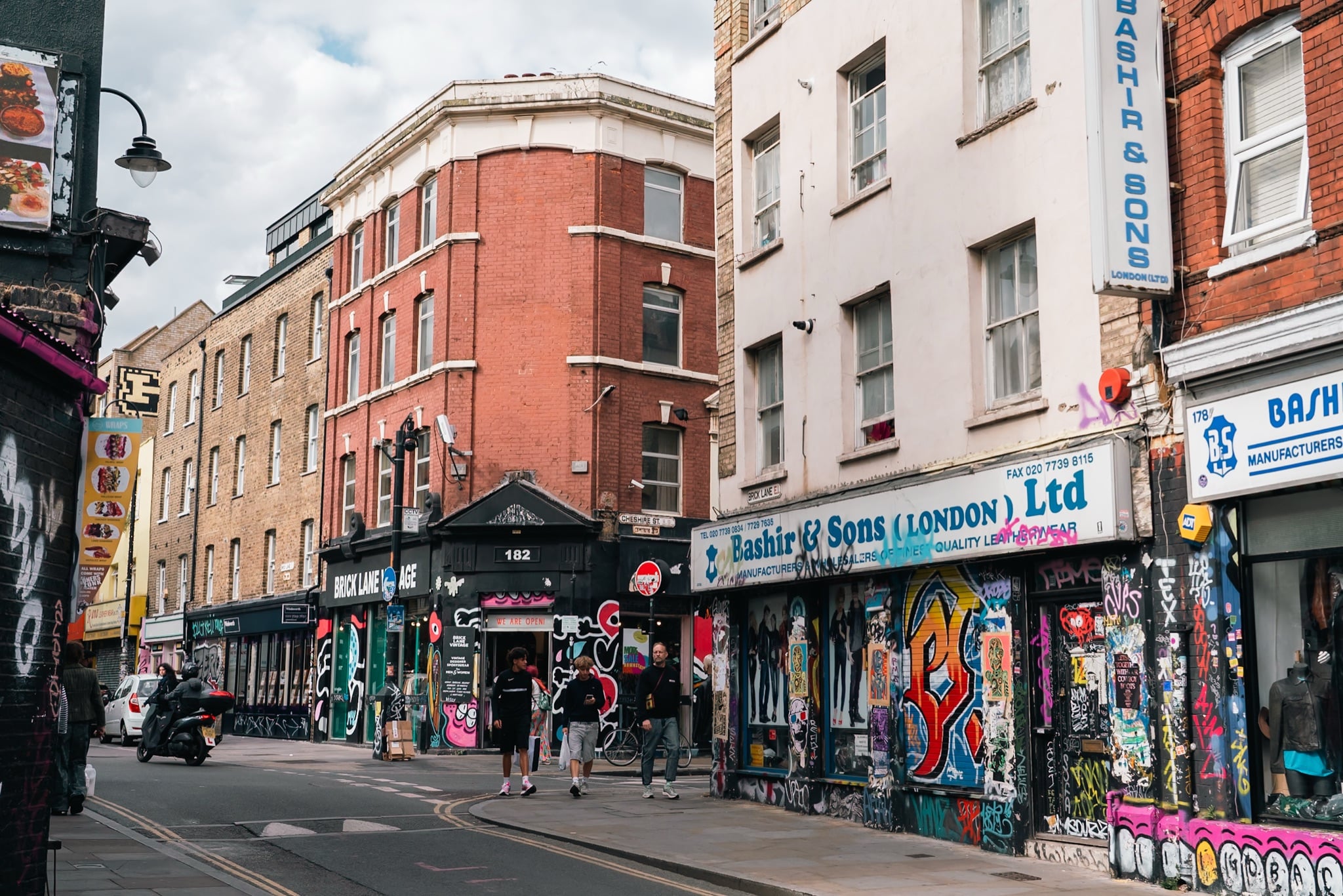 A Brick Lane street corner of vintage shops and graffiti-covered storefronts