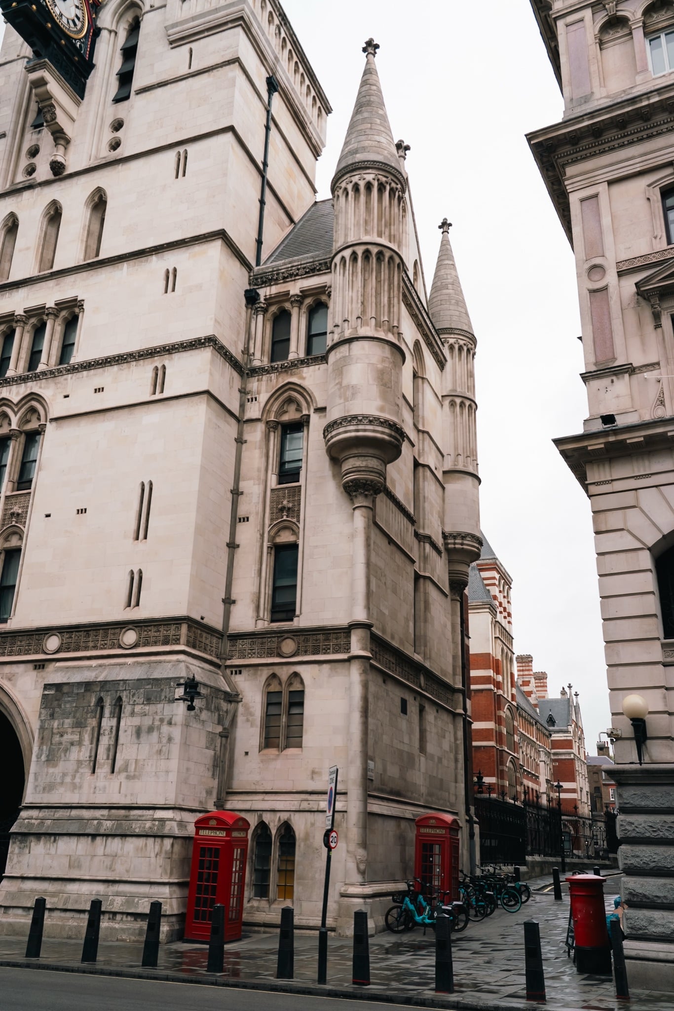 Stone turrets of the Royal Courts of Justice above two red telephone boxes and a pillar box