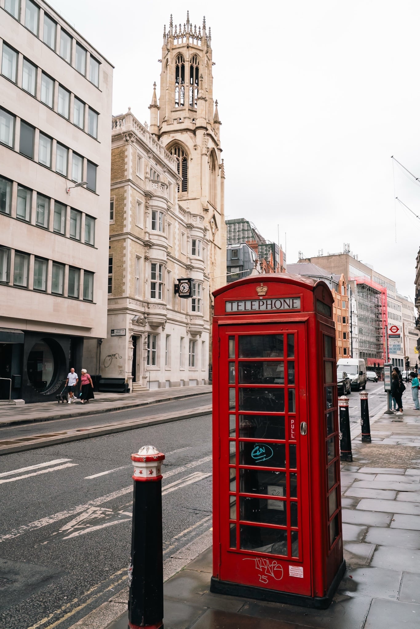 A red telephone box on Fleet Street with the Gothic tower of St Dunstan-in-the-West behind