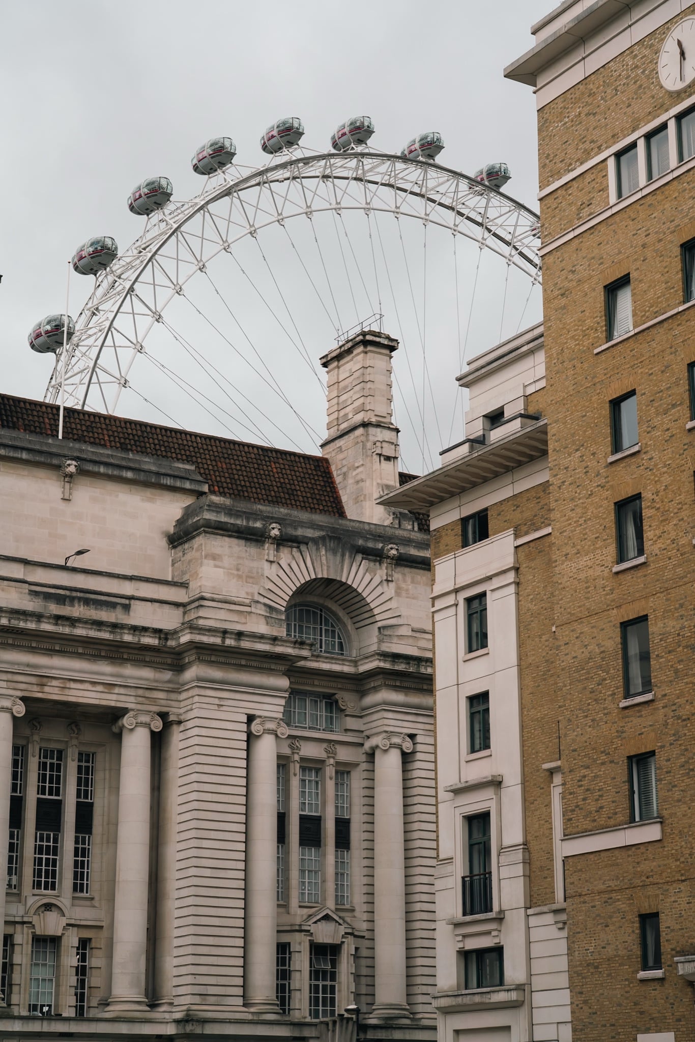 The London Eye rising behind the rooftops of County Hall, framed between buildings