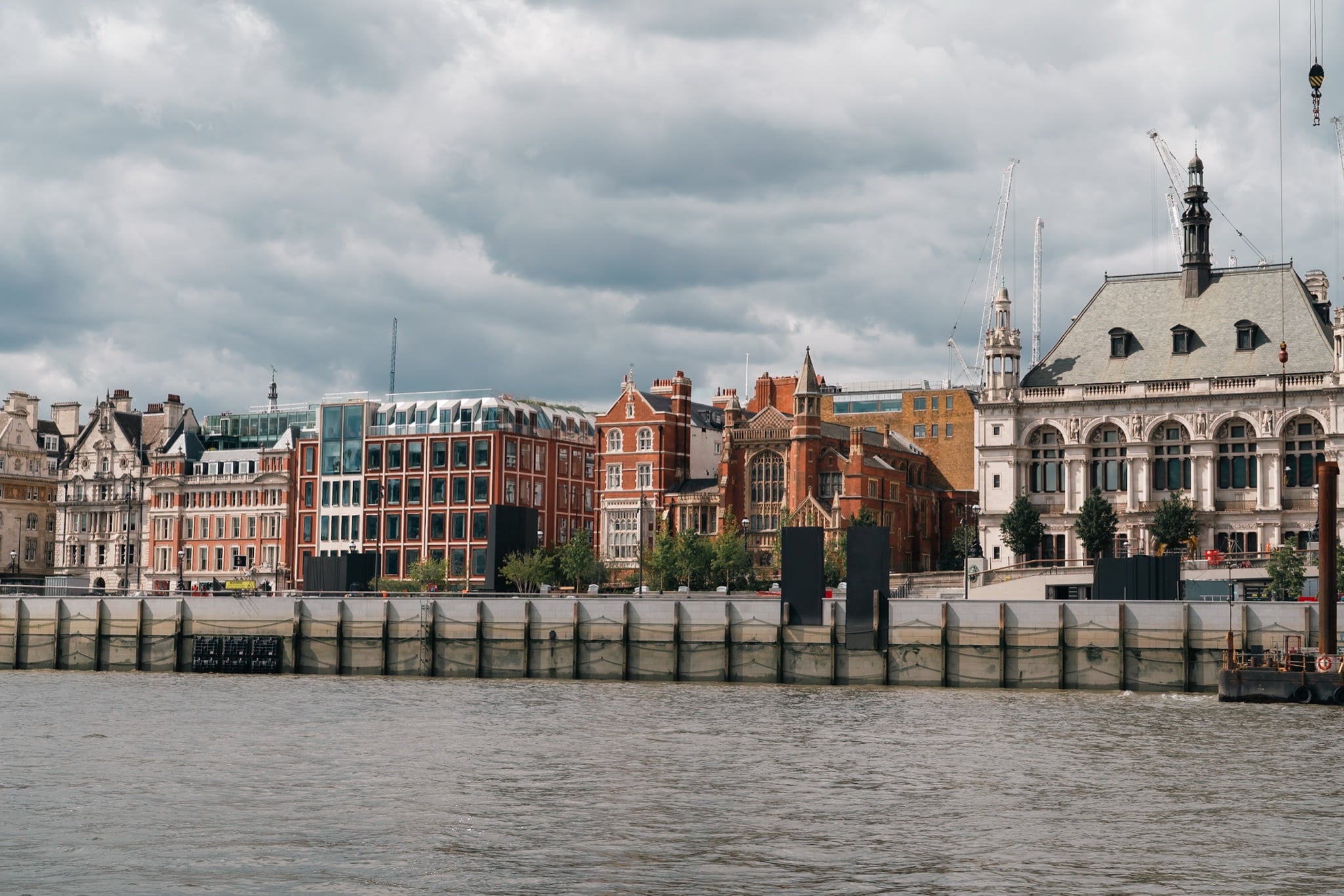 A row of red-brick and stone buildings along the Victoria Embankment seen from the Thames