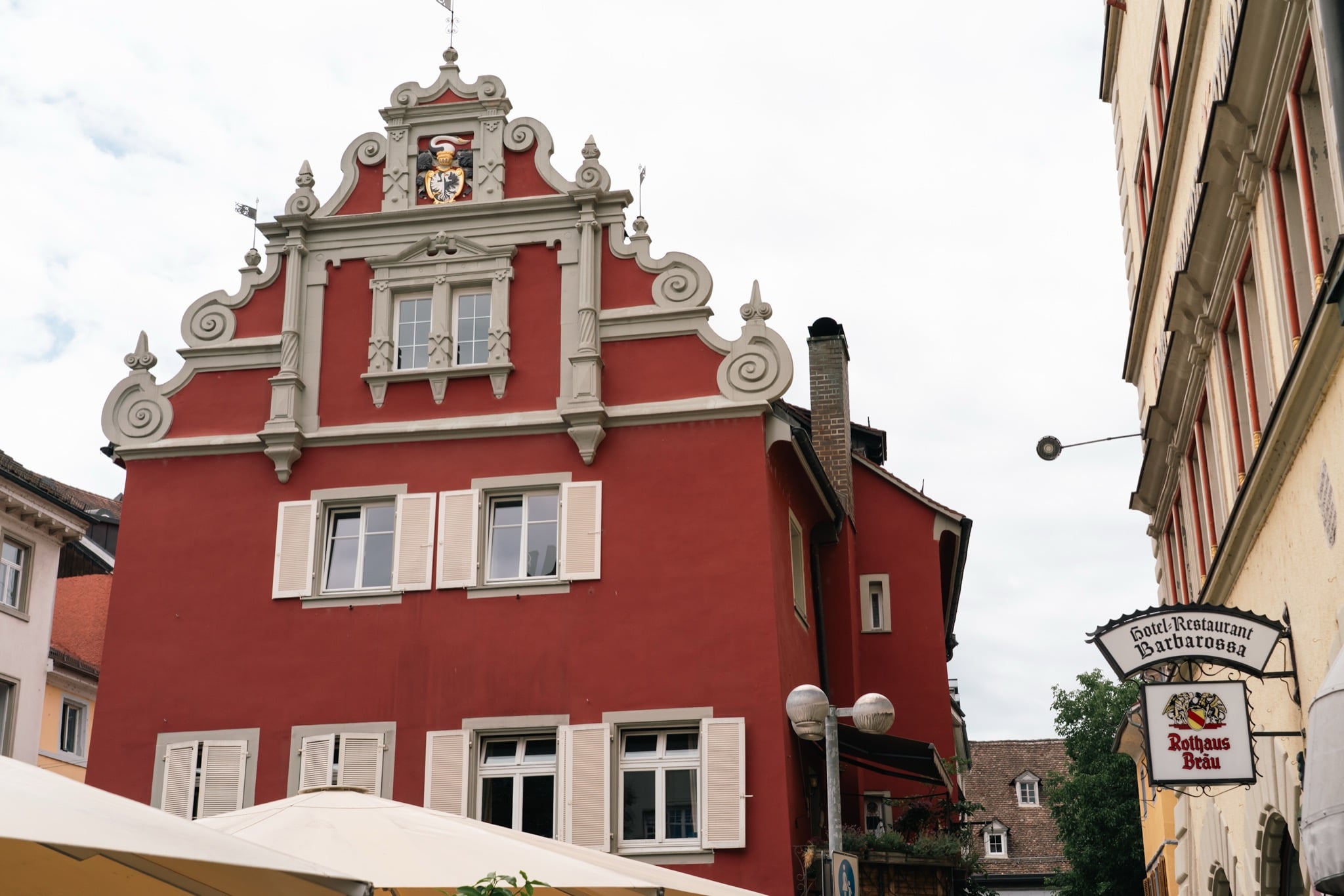 A red Renaissance house with a scrolled gable and coat of arms in old Konstanz