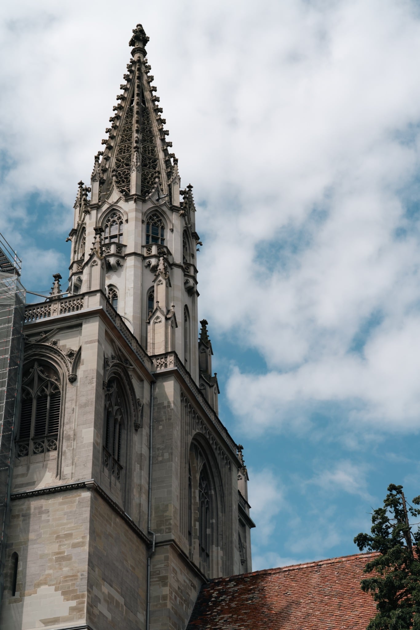 The openwork Gothic spire of the Konstanz Minster rising into a cloud-streaked sky