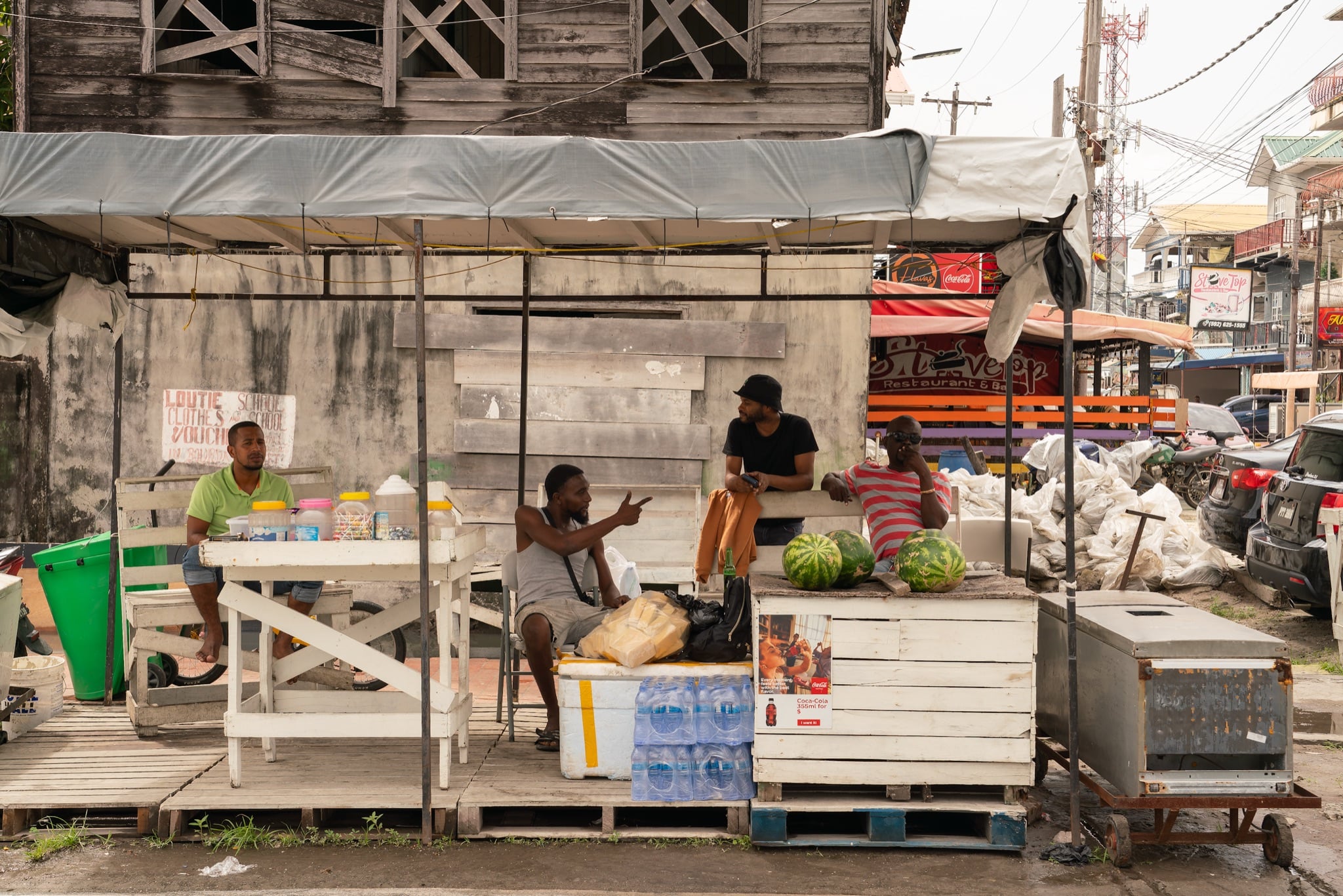 Vendors passing the time at a produce stall in Georgetown