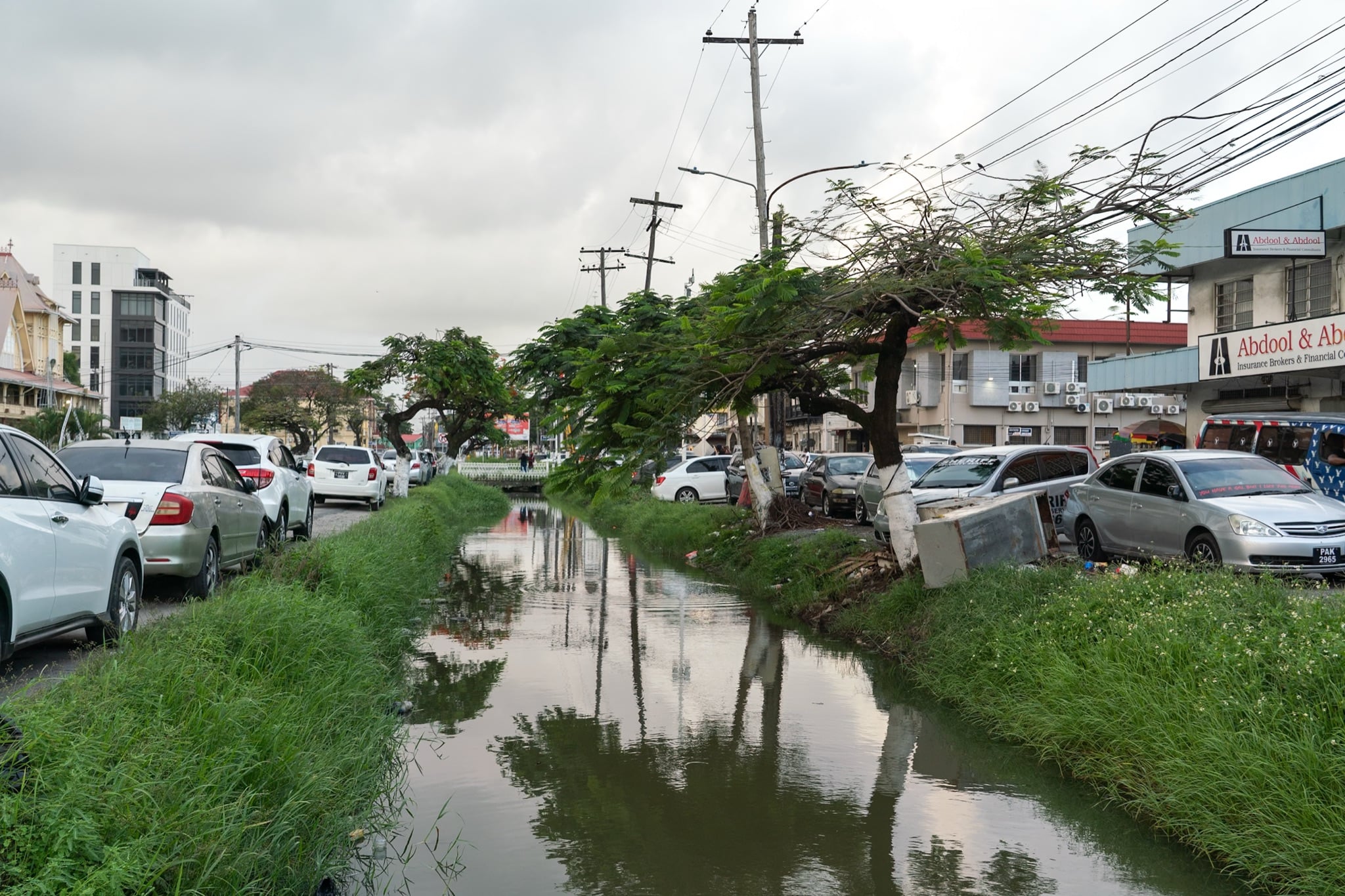 Cars lining a road beside one of Georgetown's drainage canals