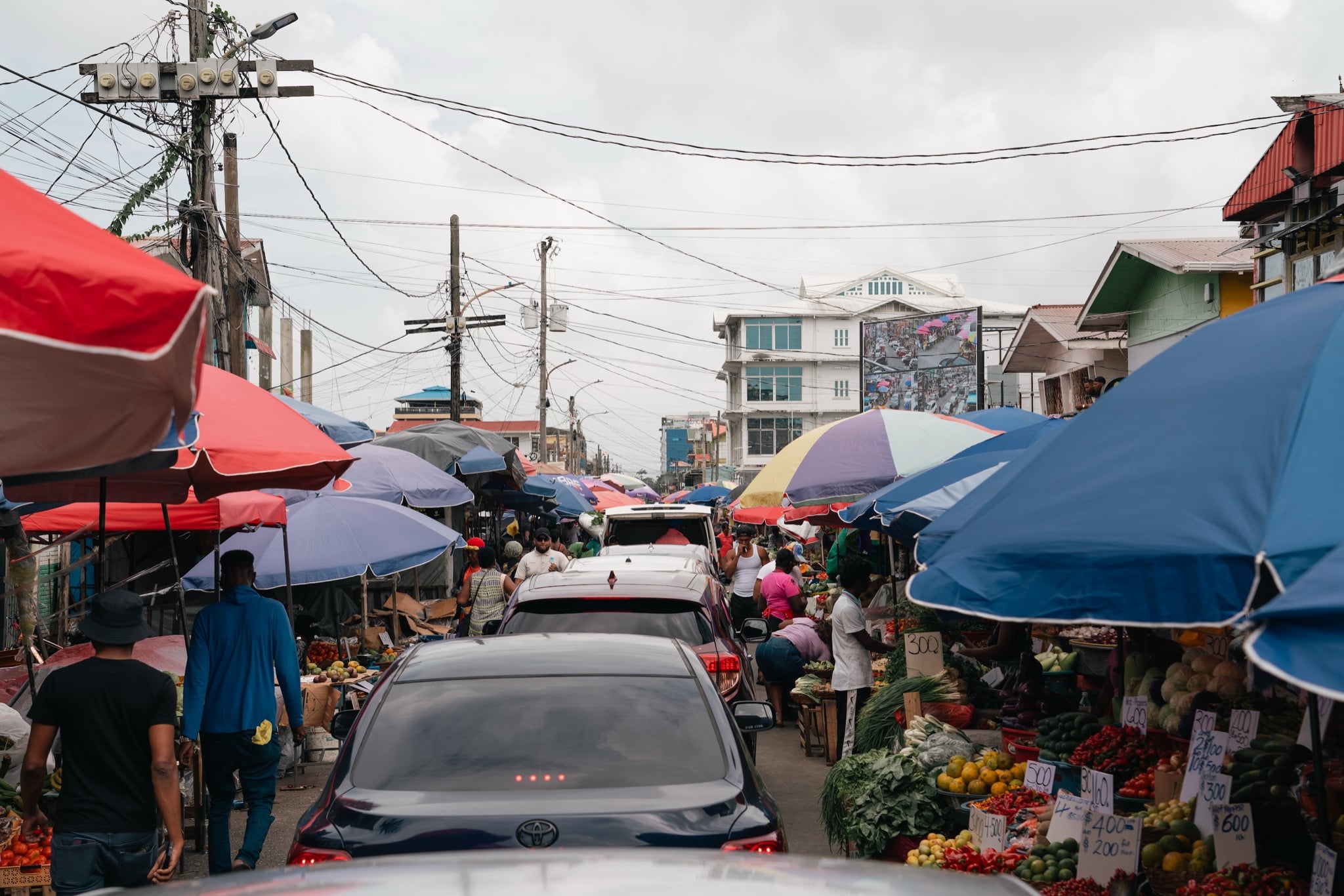 A busy market street lined with umbrellas and fruit stalls in Georgetown