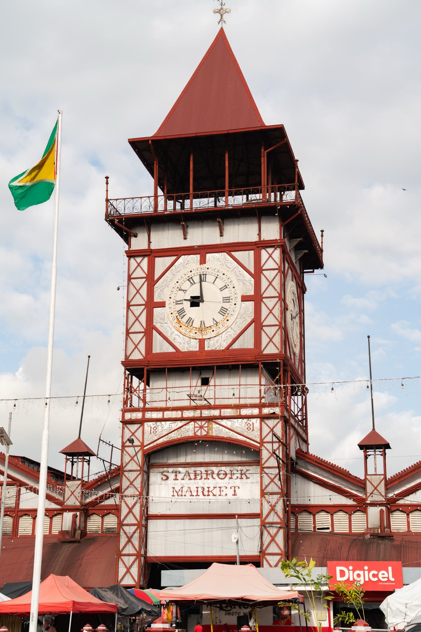 The red clock tower of Stabroek Market rising over Georgetown, the Guyana flag flying alongside