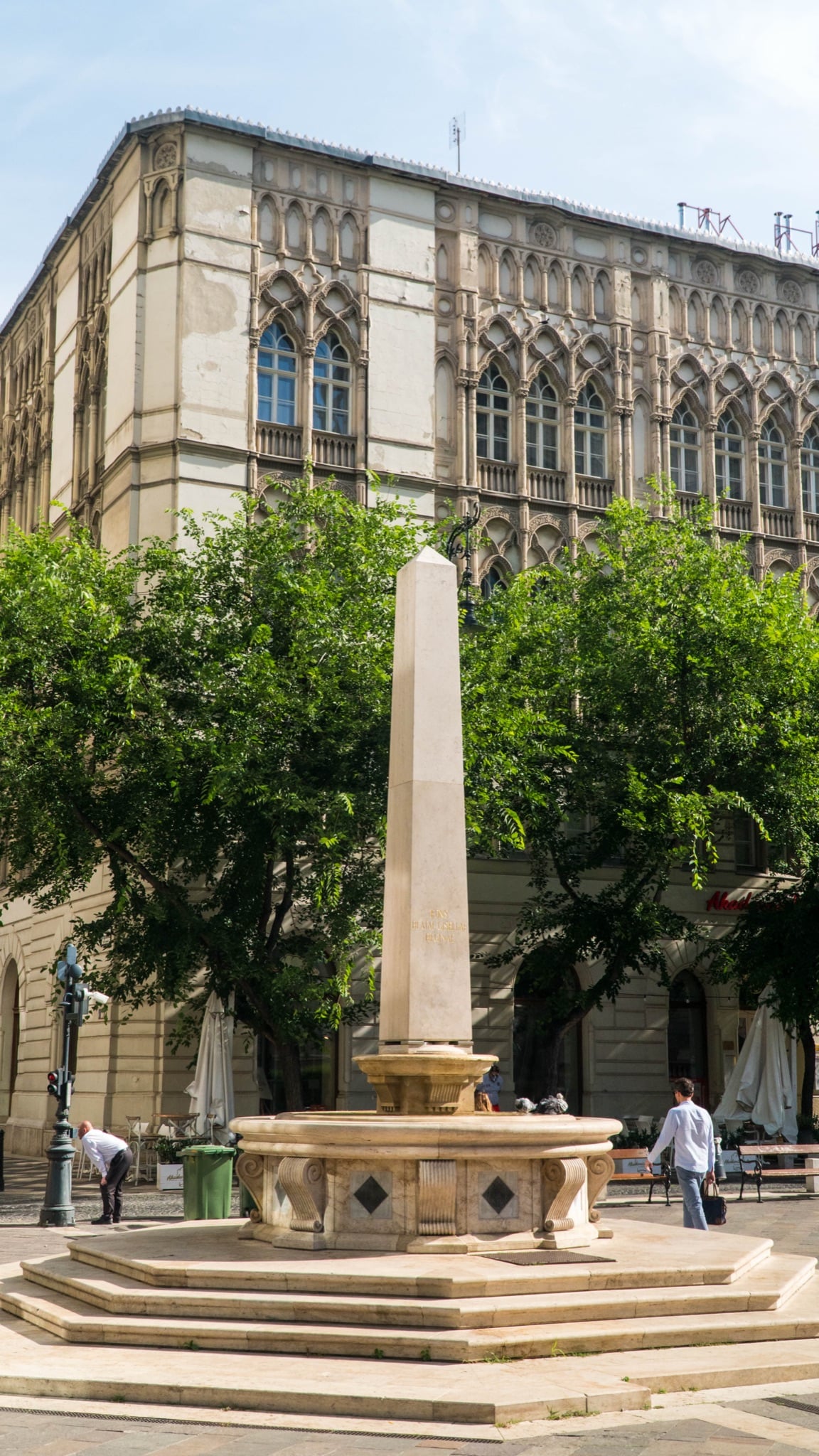 A slender obelisk fountain before a Venetian-Gothic palazzo on Szervita Square