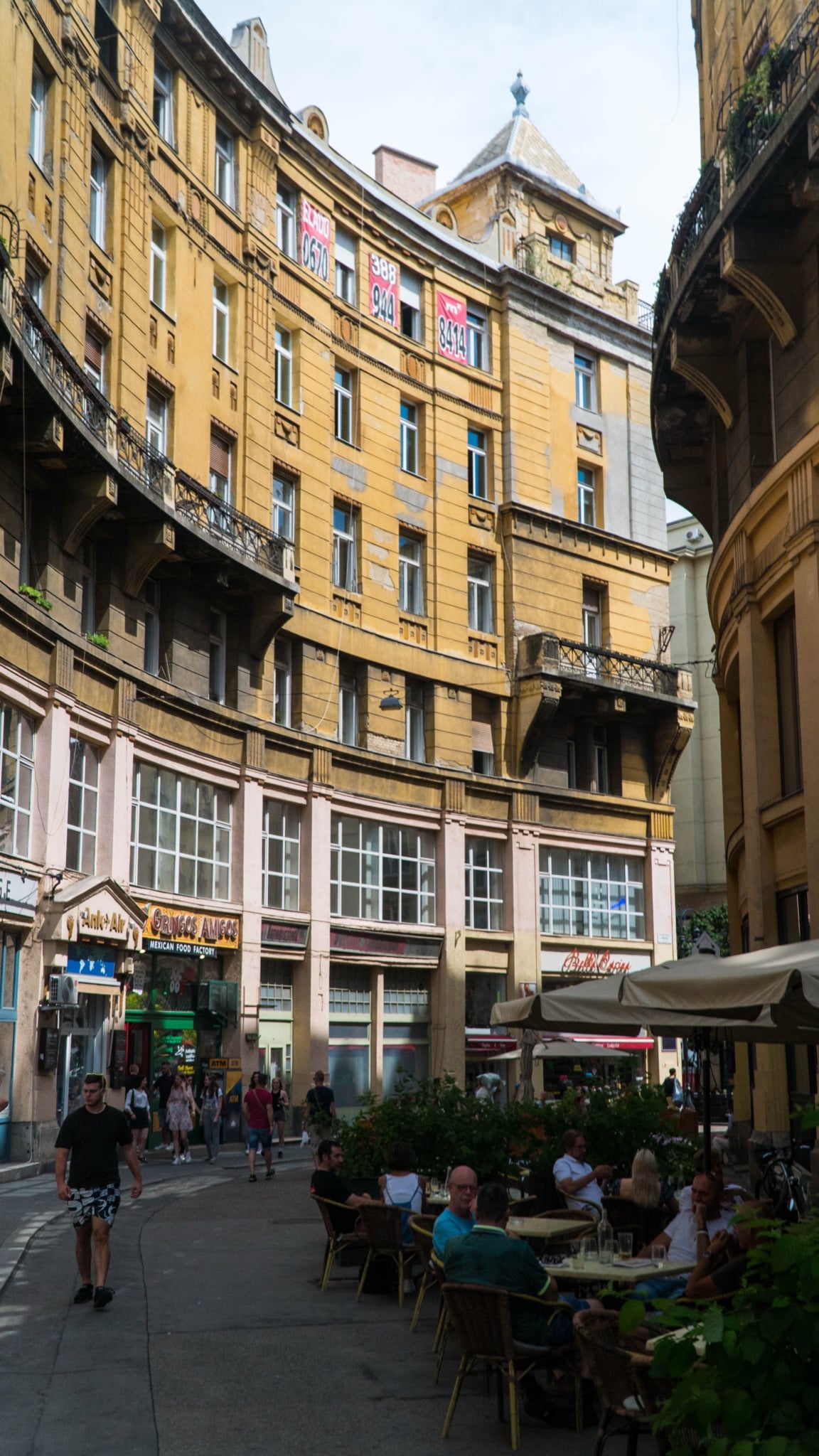 A curved cream facade wrapping a café-lined bend in the old town