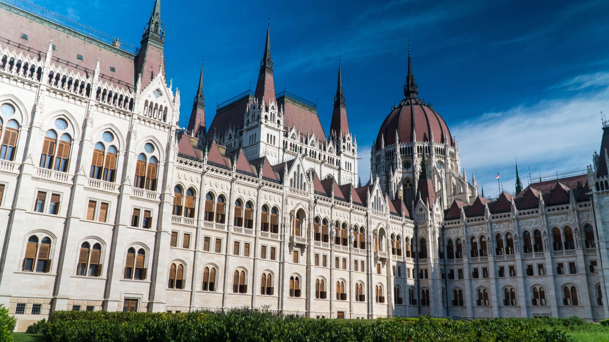 Sunlight across the white spires and red dome of the Hungarian Parliament