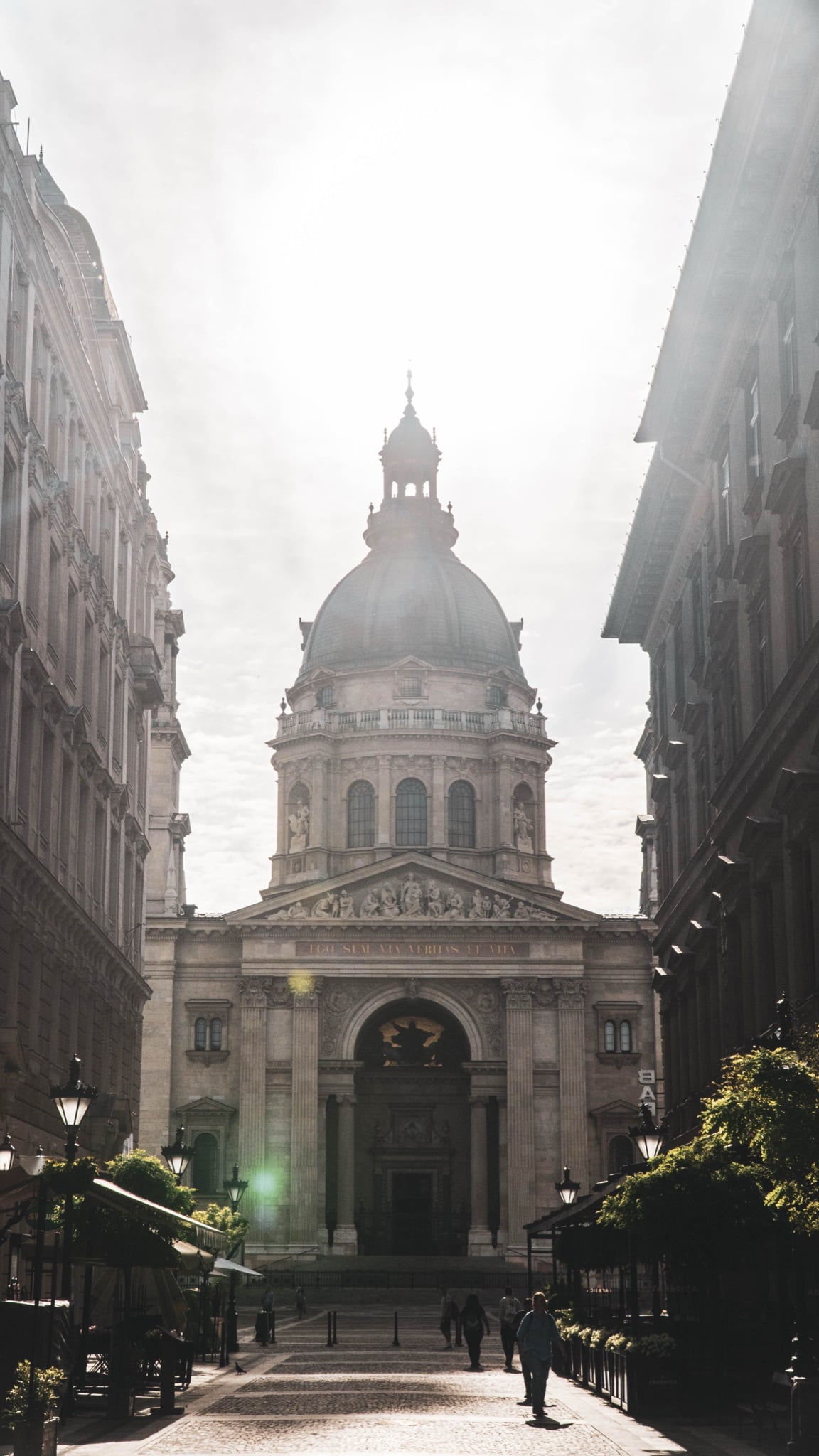 The dome of St. Stephen's Basilica silhouetted in morning haze above a quiet street