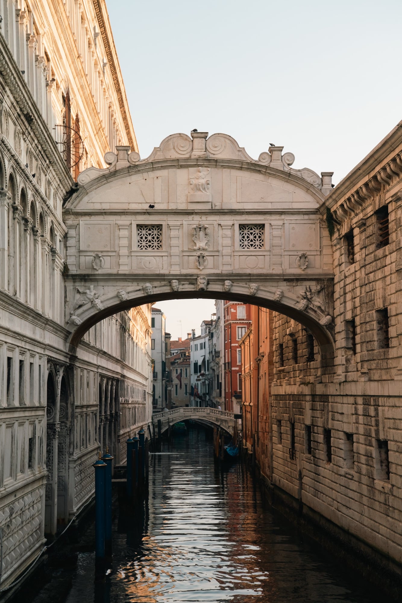 The white marble Bridge of Sighs arching over the Rio di Palazzo, a smaller bridge and colourful houses framed beneath it at golden hour