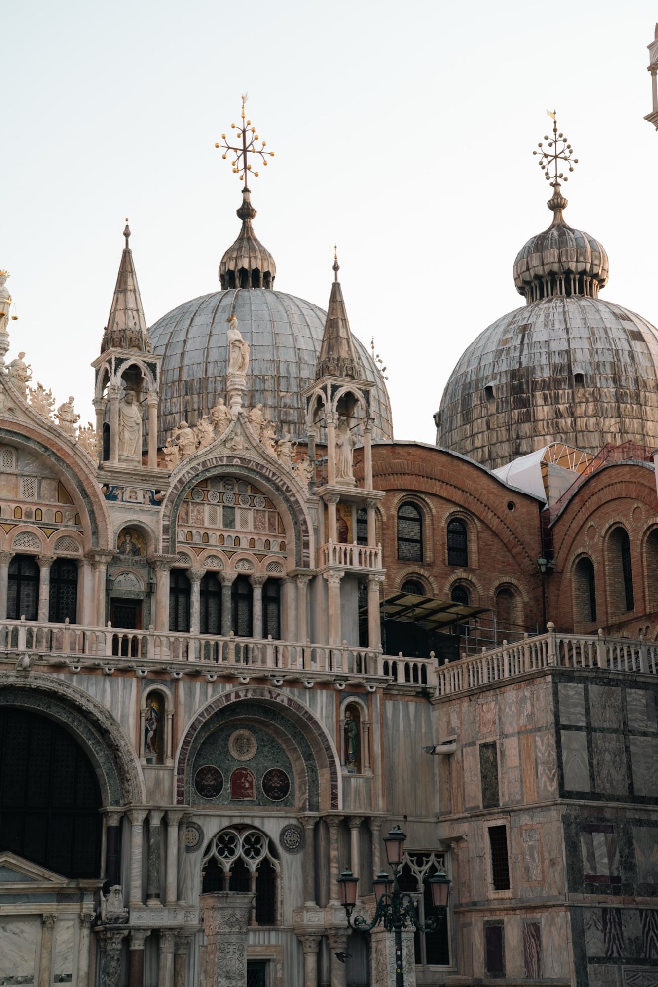 The lead-covered onion domes of St Mark's Basilica with their gilded crosses rising above the mosaic-filled Gothic upper facade