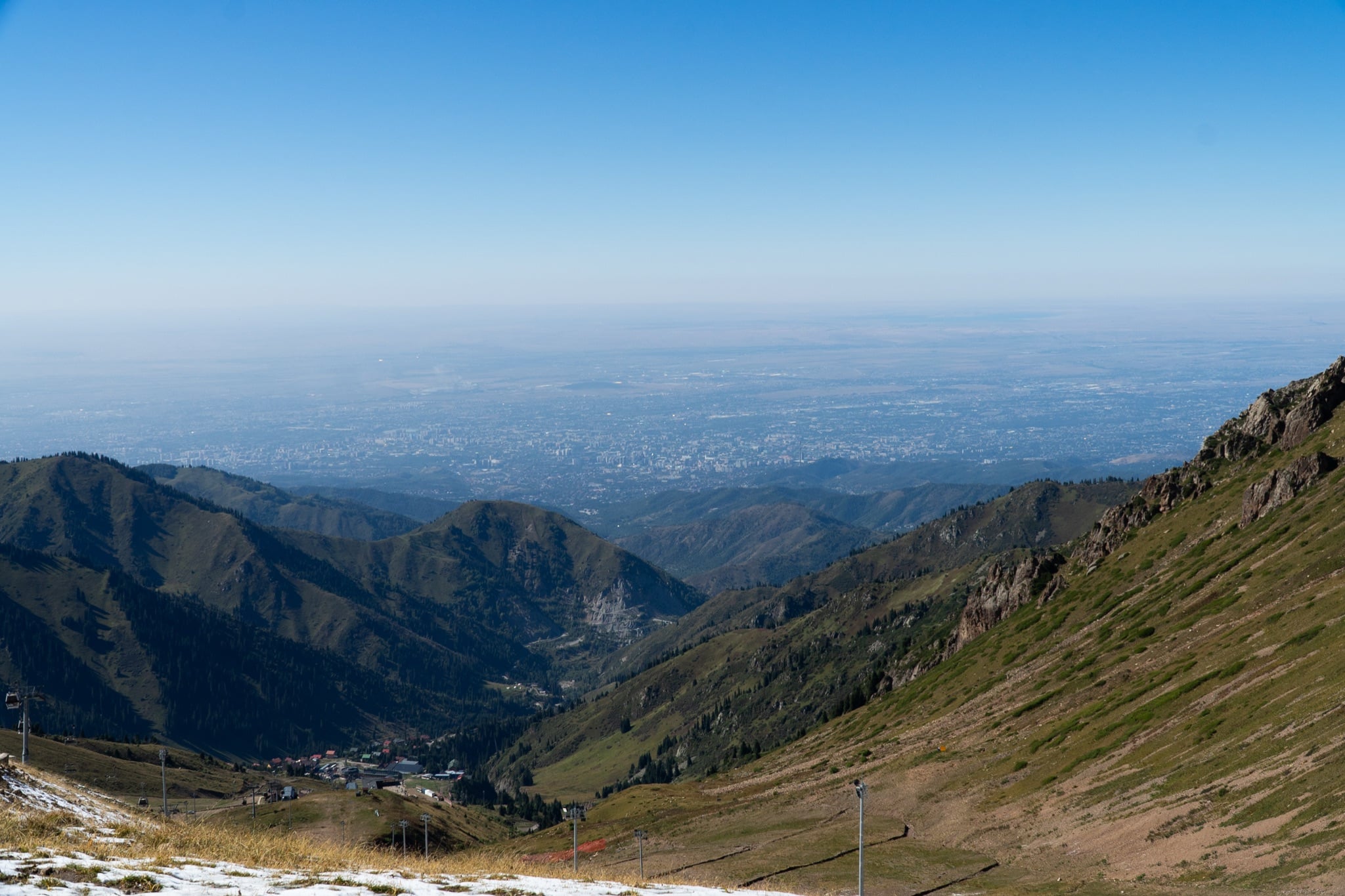The view down from Shymbulak to Almaty spread hazy across the plain far below