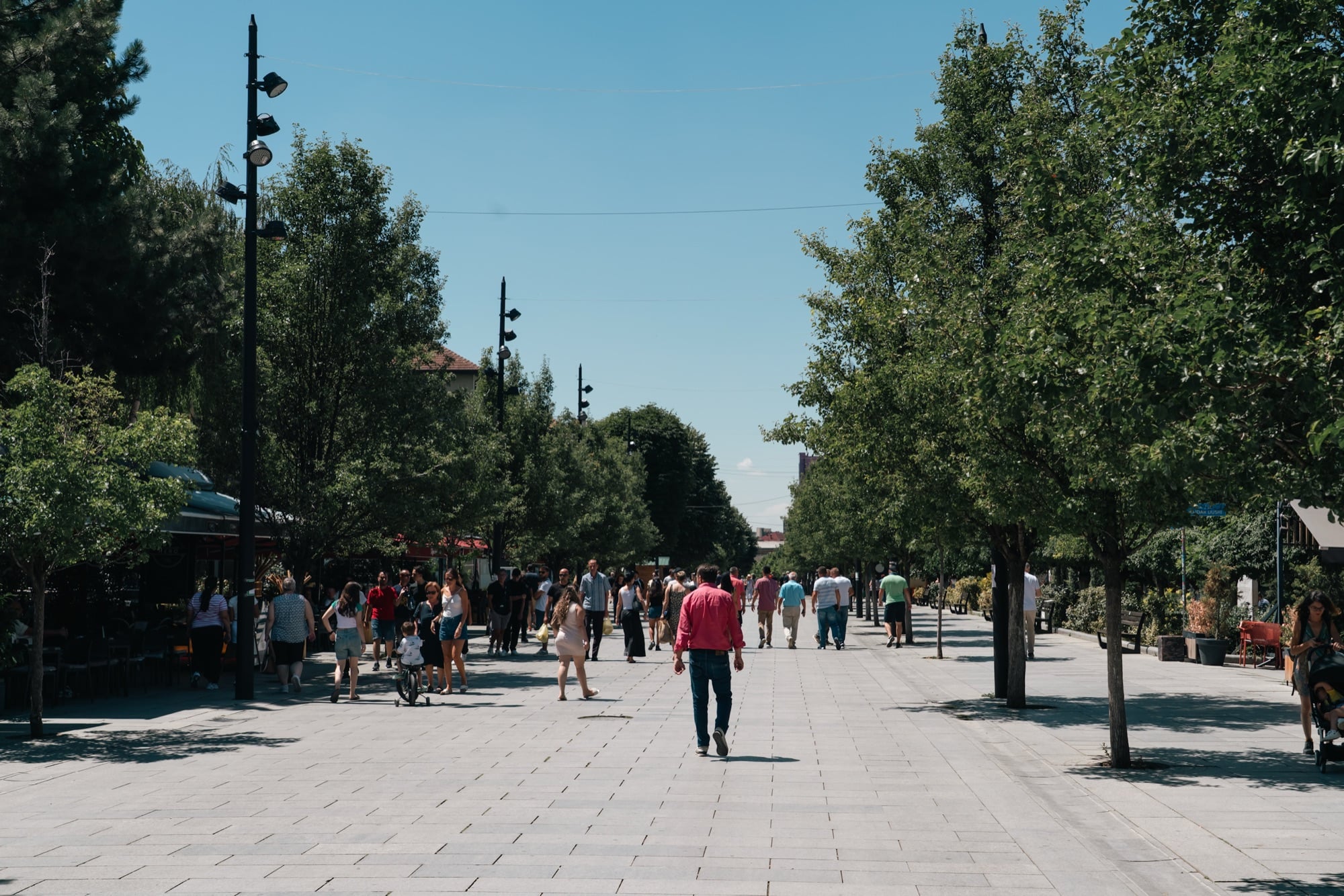 Pedestrians strolling the tree-lined Mother Teresa Boulevard in central Pristina on a bright summer afternoon