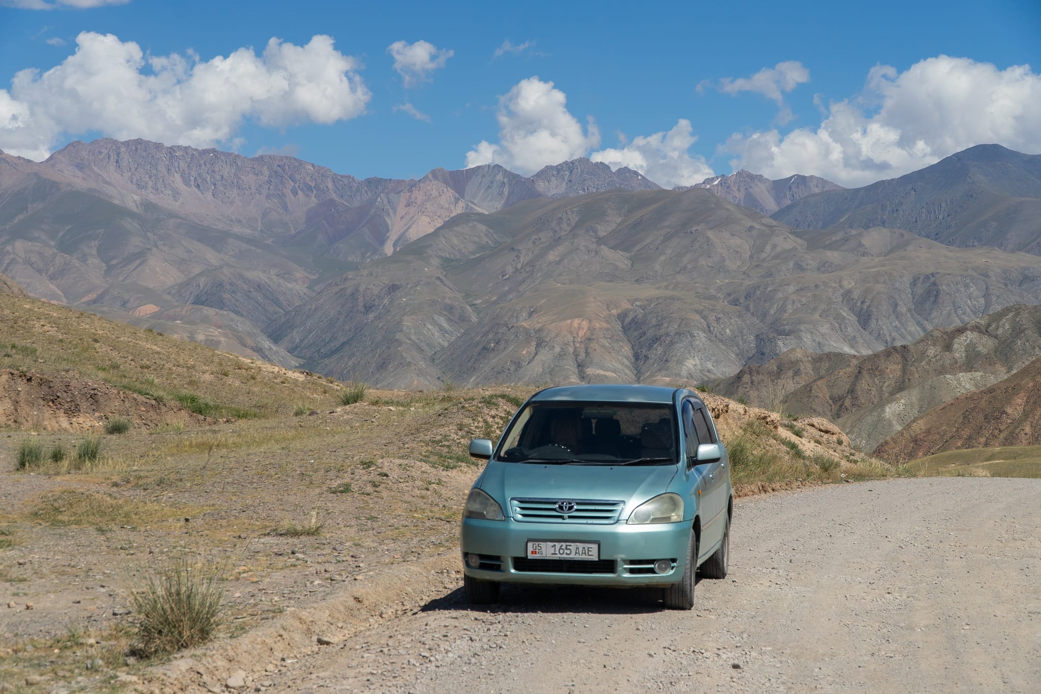 A vehicle dwarfed by the peaks on the road to Song-Kul