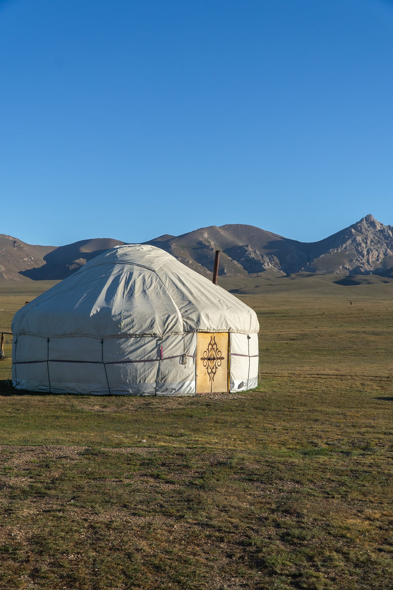 A felt yurt with its door open to the pastures at Song-Kul