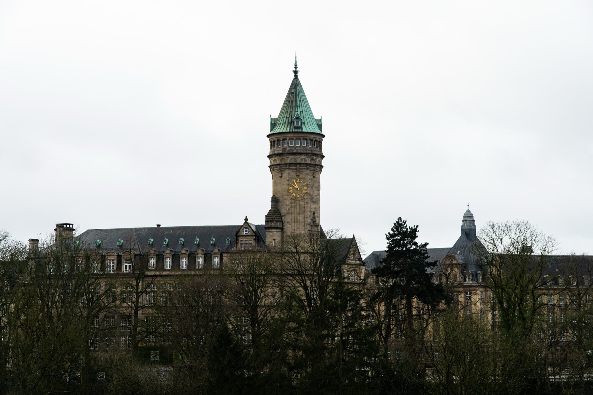 The green-domed clock tower of the State Savings Bank rising above bare winter trees, Luxembourg City