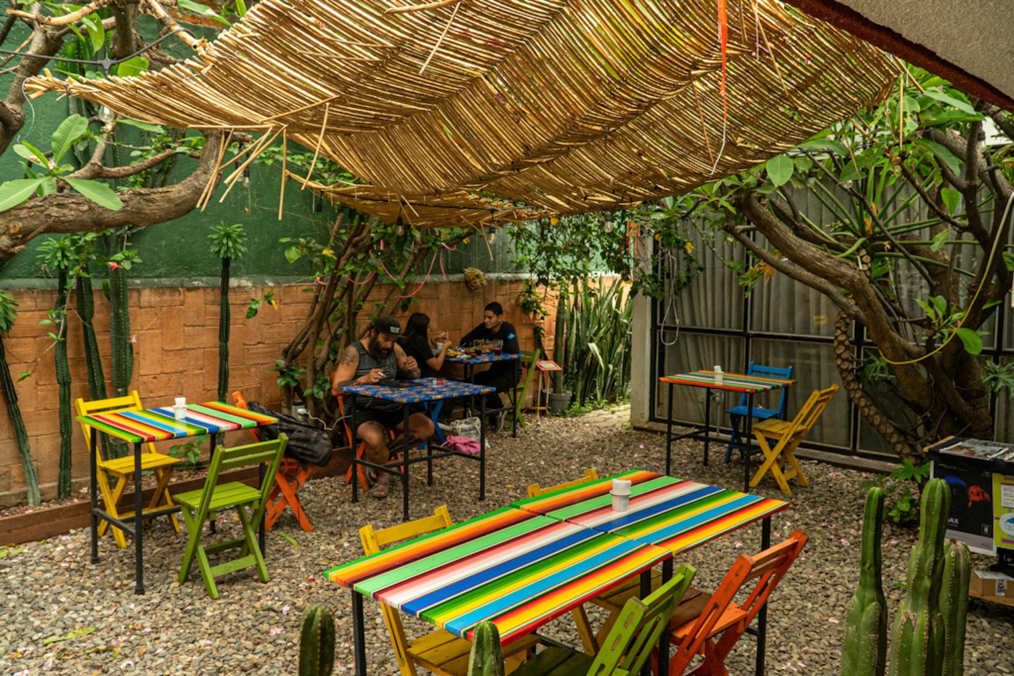 Hand-painted tables in a courtyard beneath a thatched roof