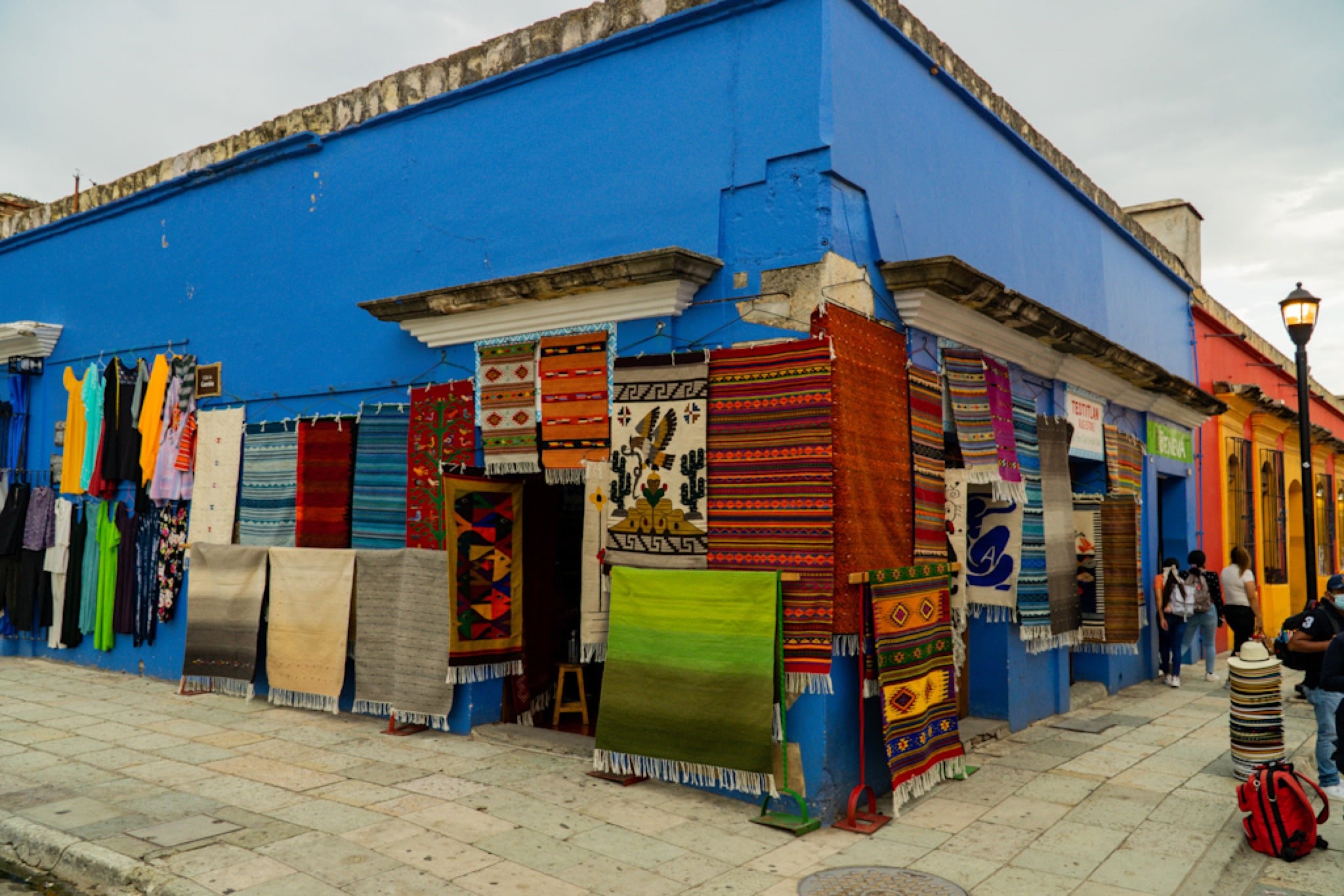 Woven textiles hung across a cobalt-blue wall