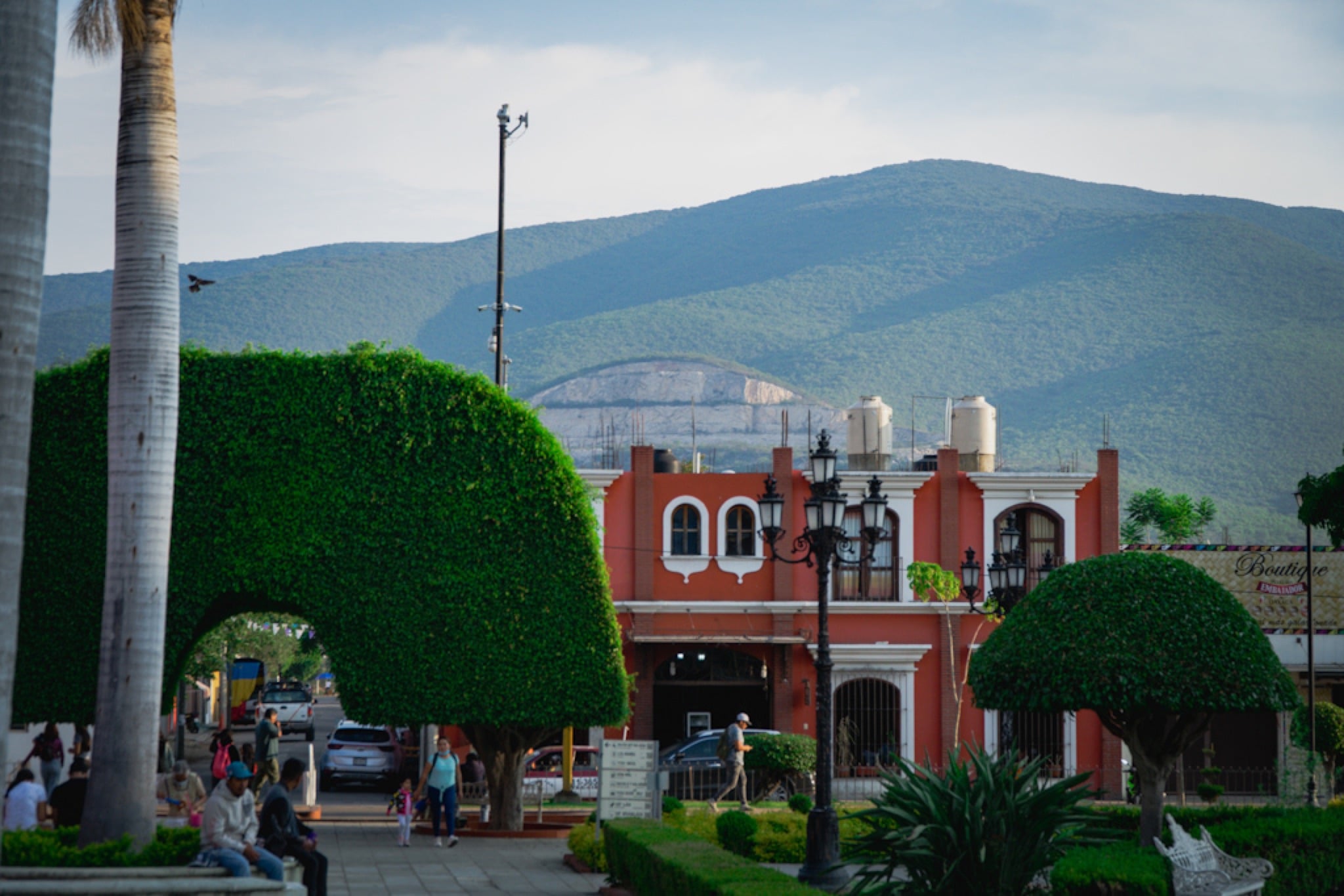A red village church behind clipped topiary