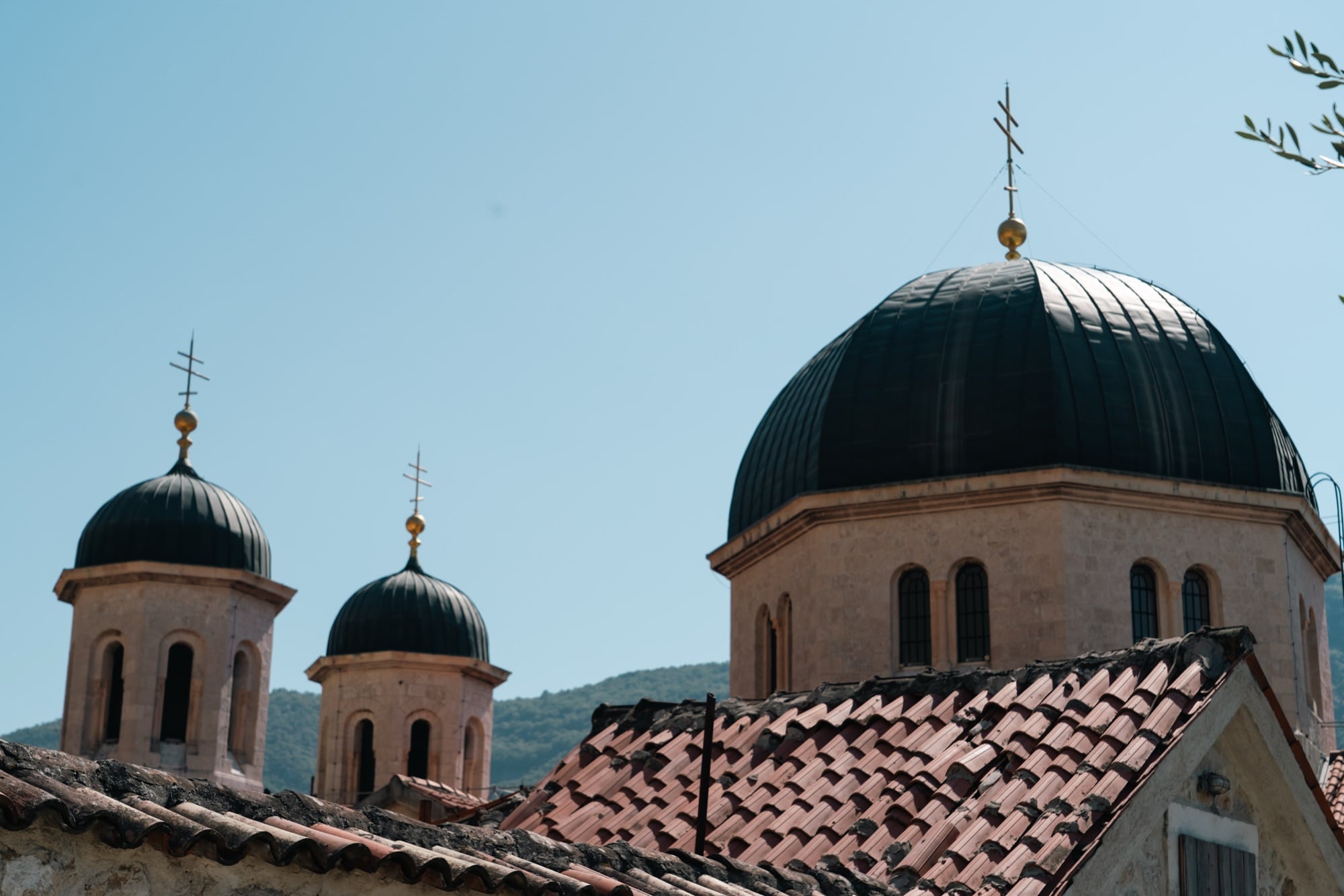 The black domes and gold crosses of Kotor's Orthodox church rising above the old town's weathered terracotta rooftops