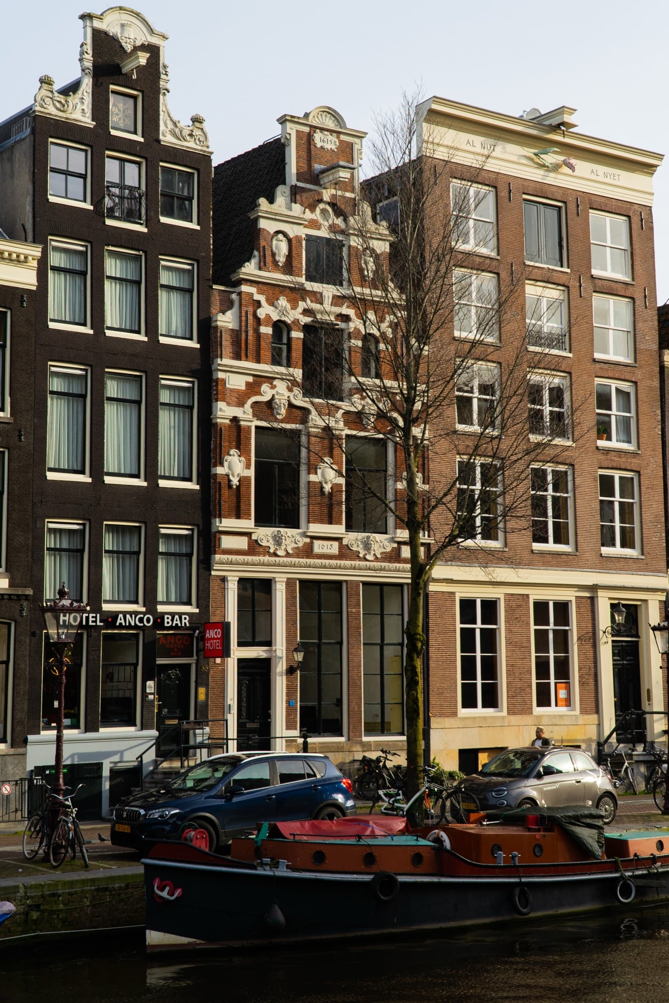 Seventeenth-century gabled houses and the Anco Hotel along a canal, a barge moored below