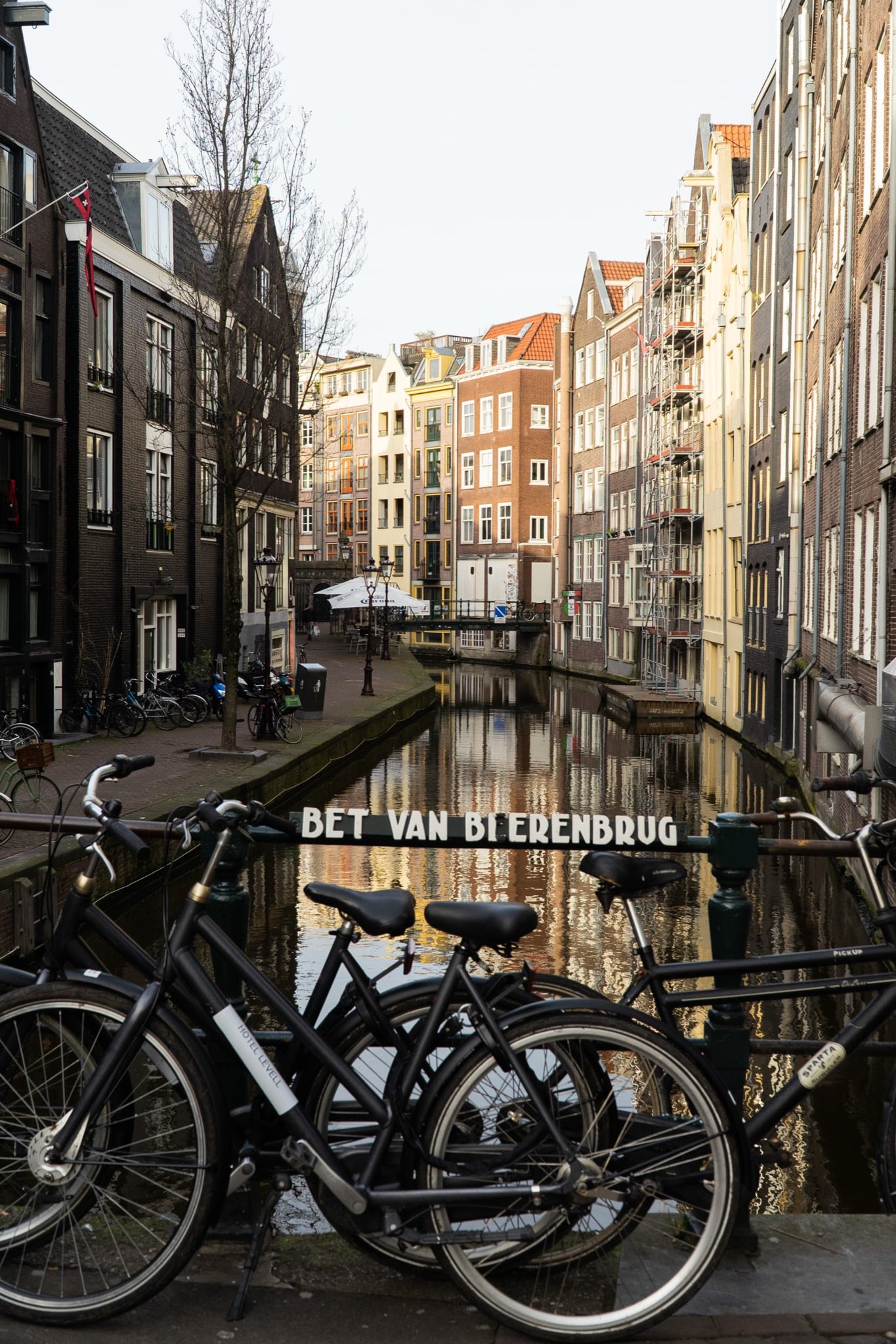Bicycles chained to a bridge railing above a narrow canal reflecting the old-centre houses