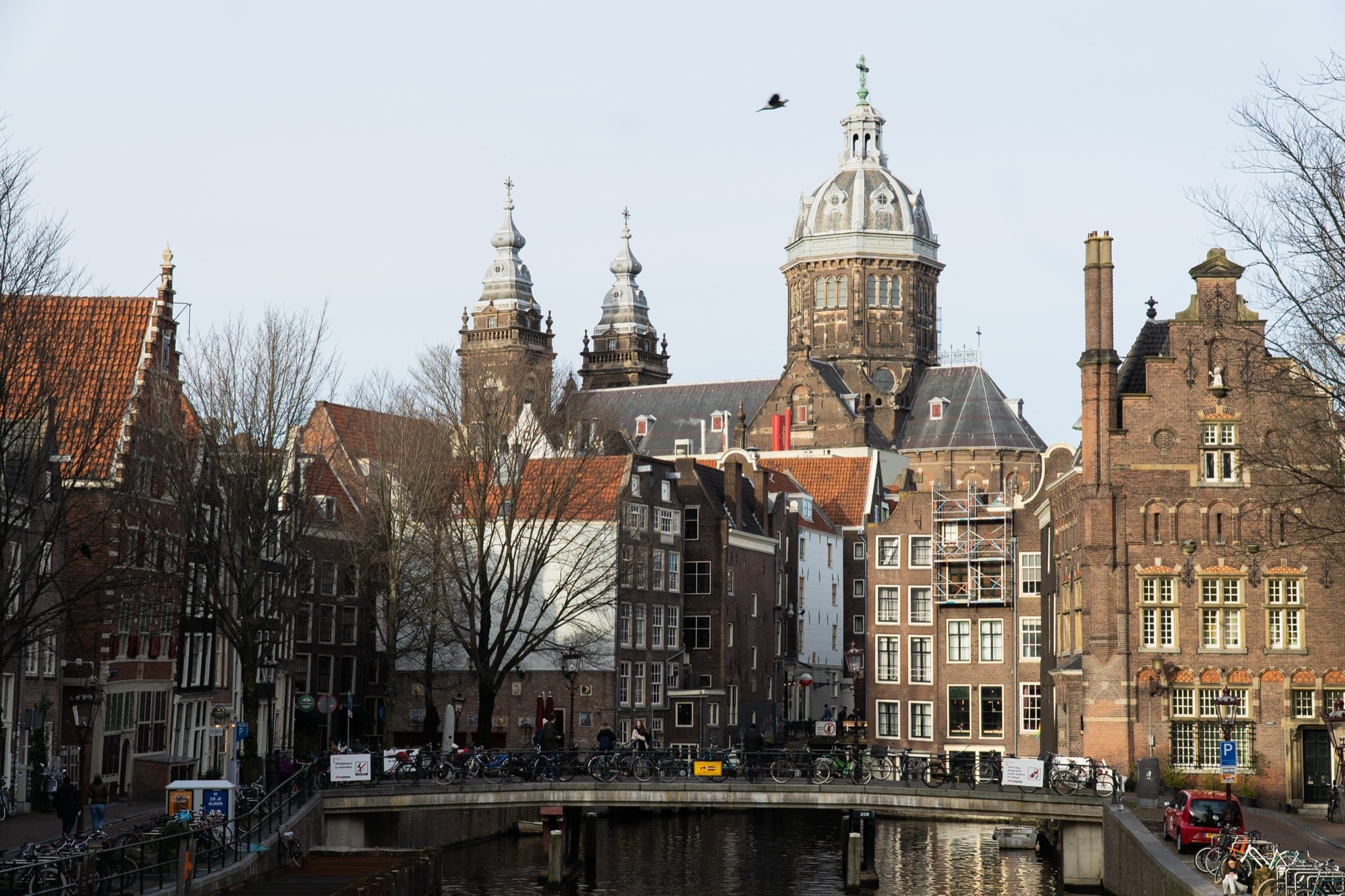 The domed towers of the Basilica of Saint Nicholas rising over a bicycle-packed canal bridge