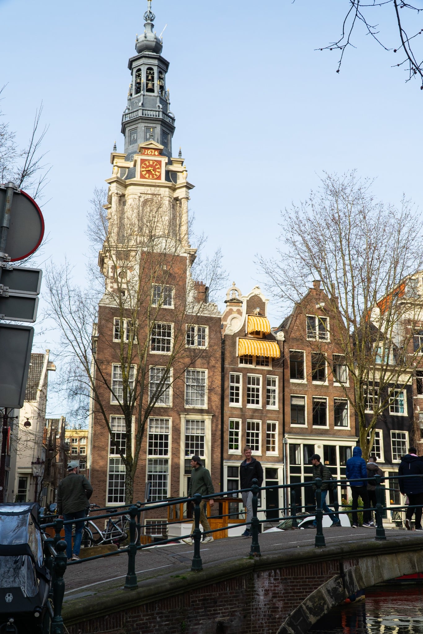The Zuiderkerk tower with its gilded clock rising above canal houses beyond a bridge