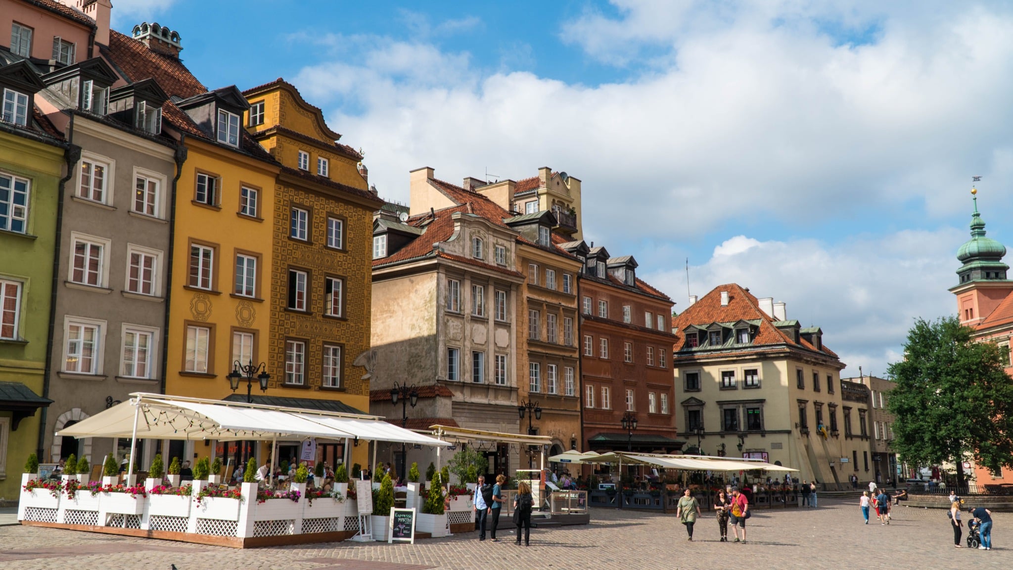 Colourful townhouses and café awnings near Castle Square, the Royal Castle tower at right