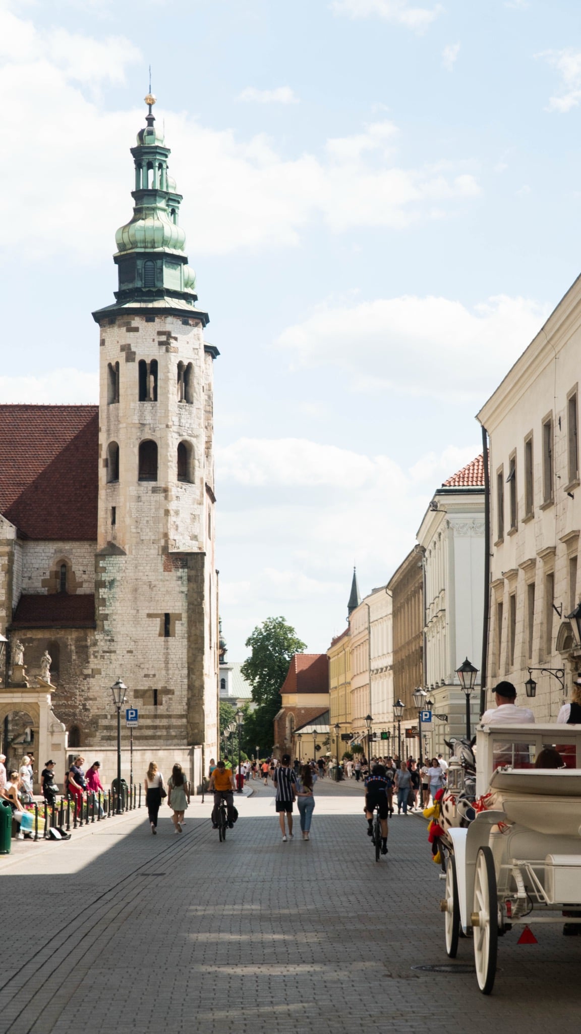 The tower of the Church of St. Andrew above Grodzka Street as a horse carriage passes