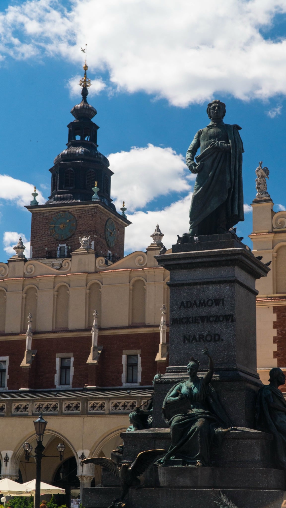 The bronze Adam Mickiewicz Monument on Kraków's Main Square, the Town Hall Tower and Cloth Hall rising behind