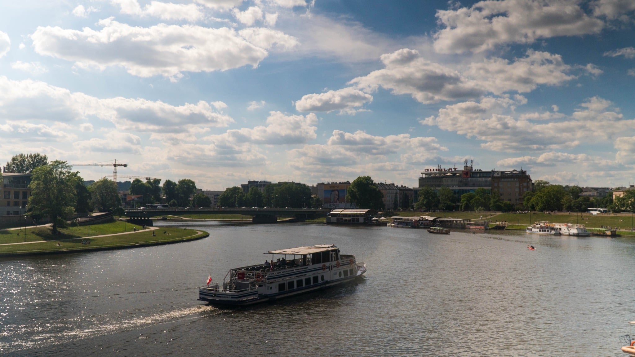 A cruise boat on the Vistula River with the Jubilat building on the far bank